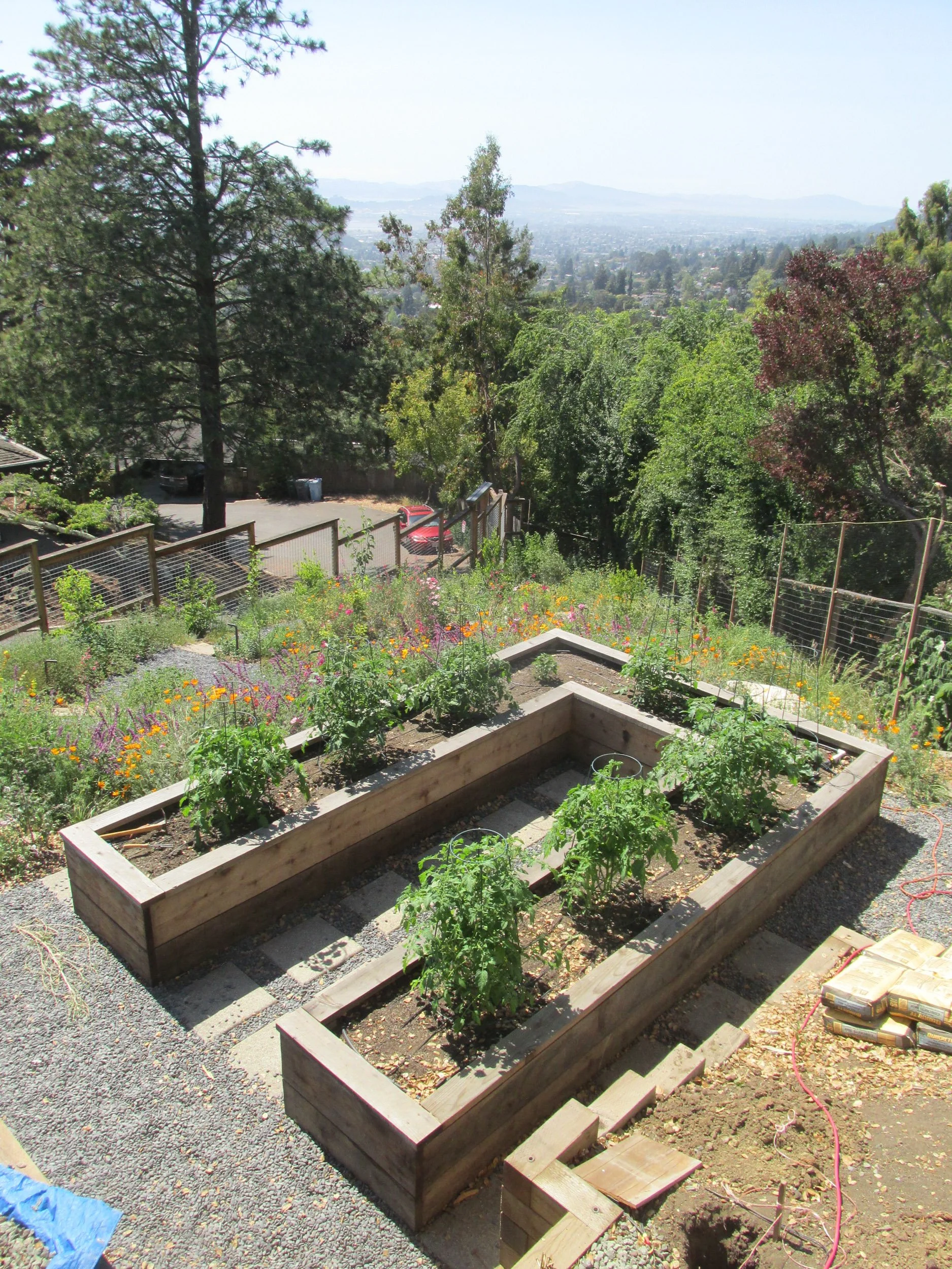 Wood custom built keyhole garden raised vegetable beds with a gravel pathway and pavers.
