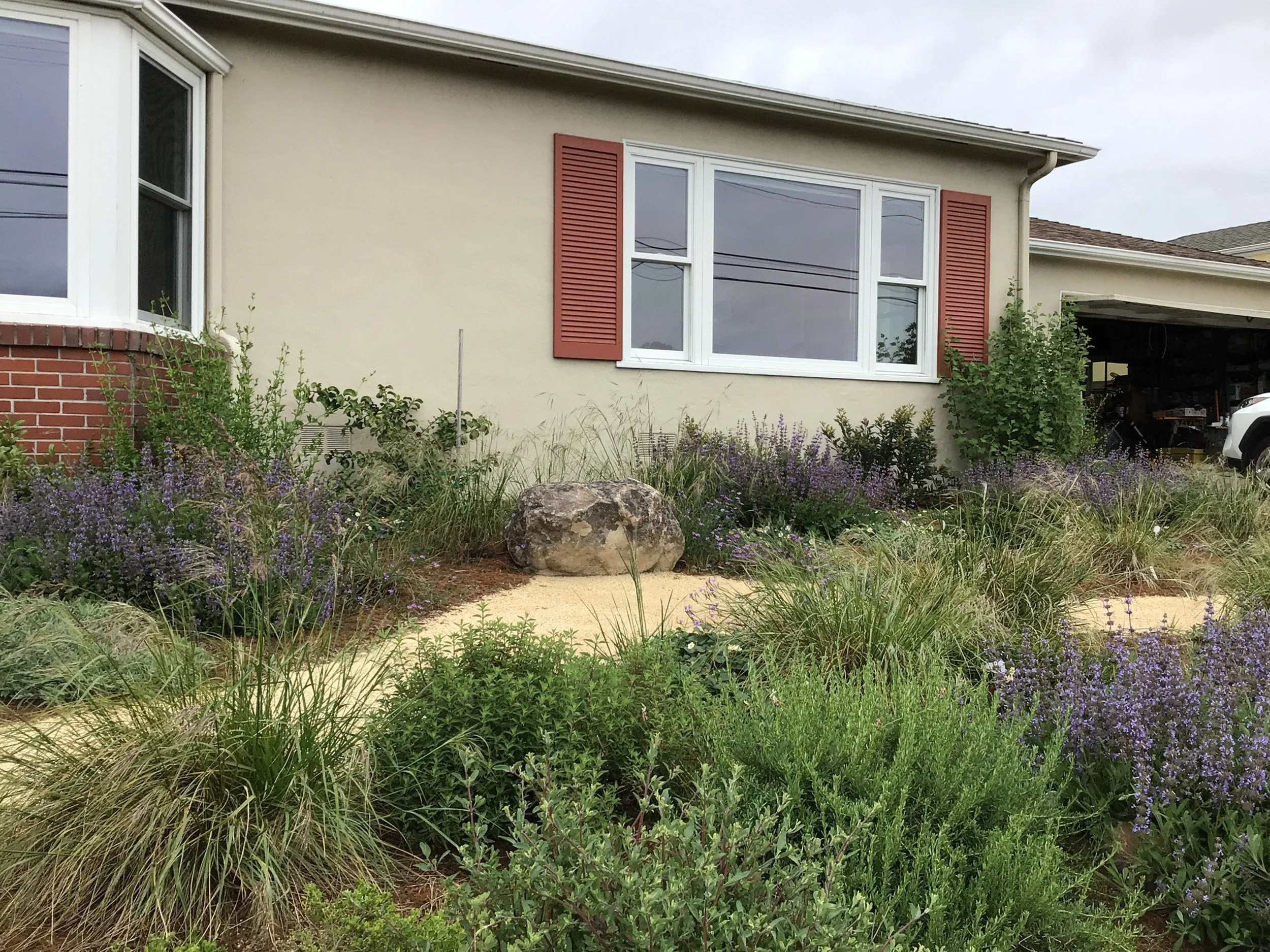 Boulder seat bench in front garden california native landscape with decomposed granite pathway