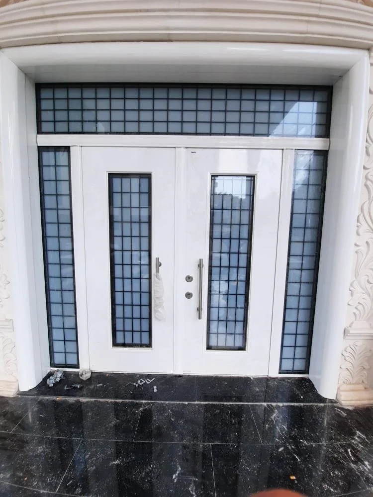 White door with glass panels and grid design, surrounded by black tile flooring.