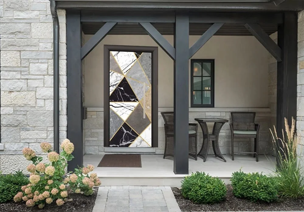 Ön verandada, siyah, beyaz, altın ve gri parçalardan oluşan geometrik cam tasarımlı, siyah ahşap çerçeveli bir kapı bulunuyor; veranda taş duvarla çevrili ve üzerinde saksı bitkileri ve dış mekan mobilyaları yer alıyor.