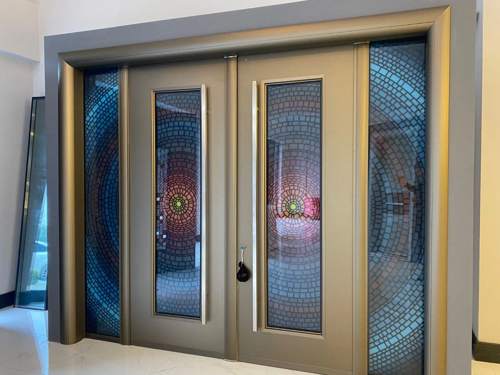 Elevator with decorative glass doors featuring circular mosaic patterns in blue, purple, and pink colors.