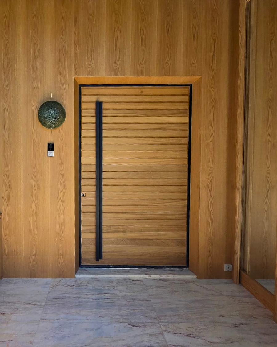 Wood-paneled wall with a sliding barn door, a textured round wall lamp, and a light switch on the wall.