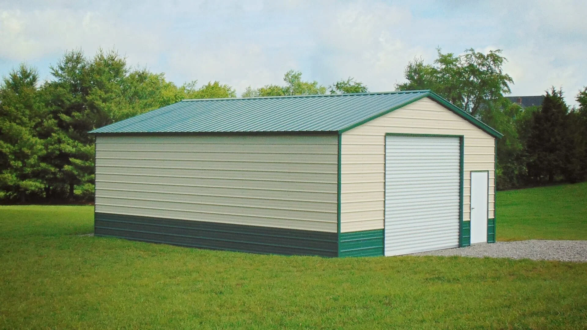 Metal storage building with green roof and roll-up door on grassy area.
