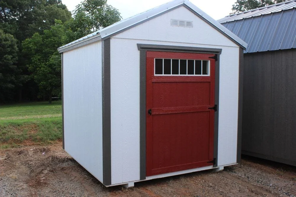 Small white shed with red door