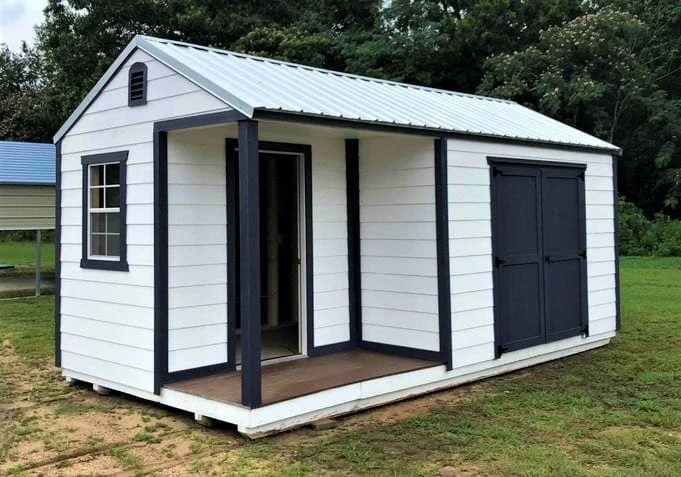 Small white shed with a blue metal roof, open door, and large double doors on grassy lawn.