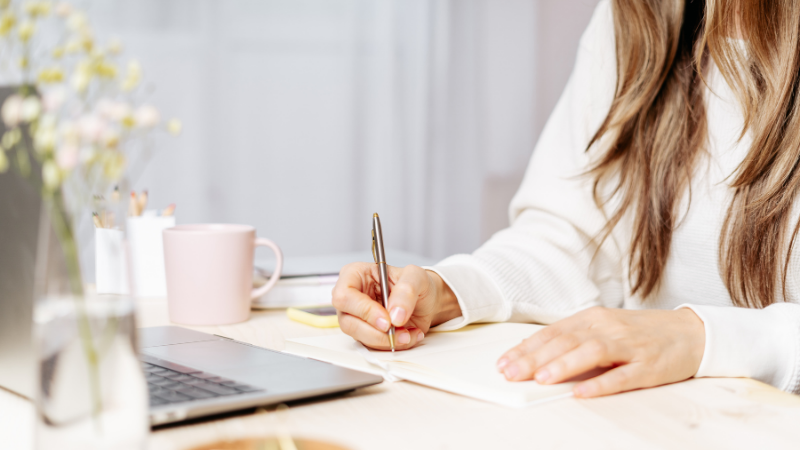 A therapist writes attentive notes, representing the warm, collaborative intake process where client history and patterns begin to take shape.