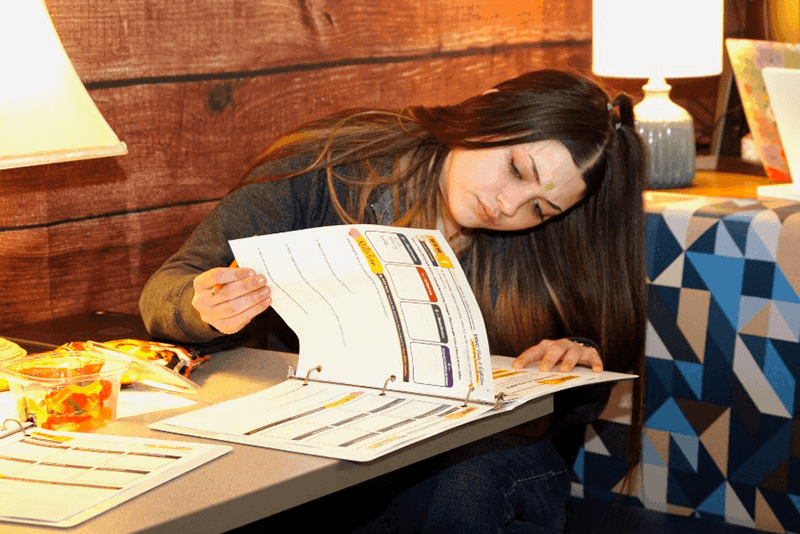 girl with long brown hair working on papers in a binder