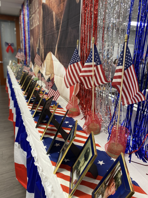 Table decorated with American flags, framed photos, and red, white, and blue streamers for a patriotic celebration.