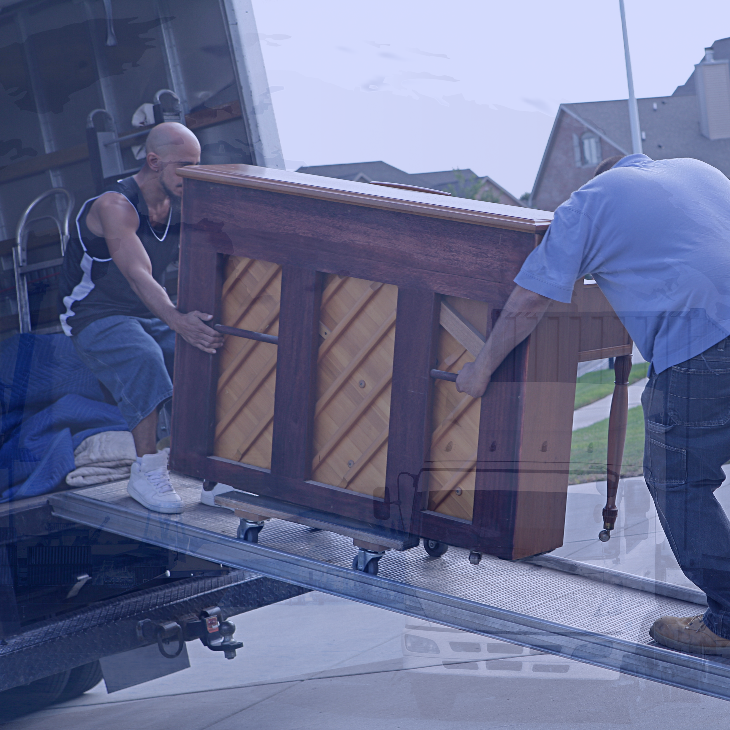 Two men moving an upright piano into a truck using a ramp.