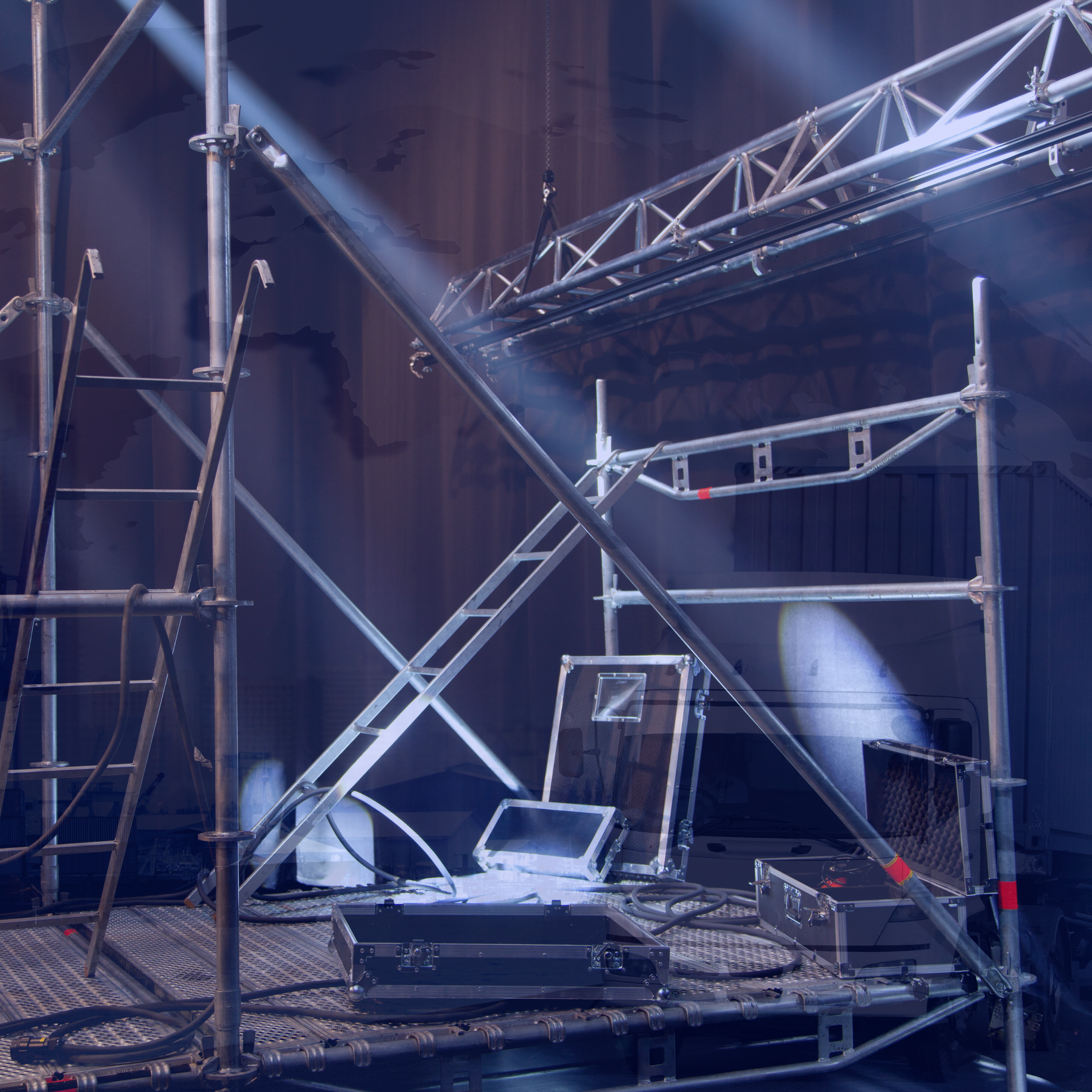 Stage scaffolding with electronic equipment and metal trusses in a dark room.