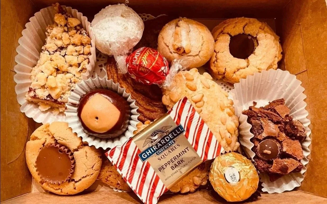 Assorted cookies and chocolates in a box, including peanut butter, chocolate chip, oatmeal, crumbly, and peppermint bark flavors.