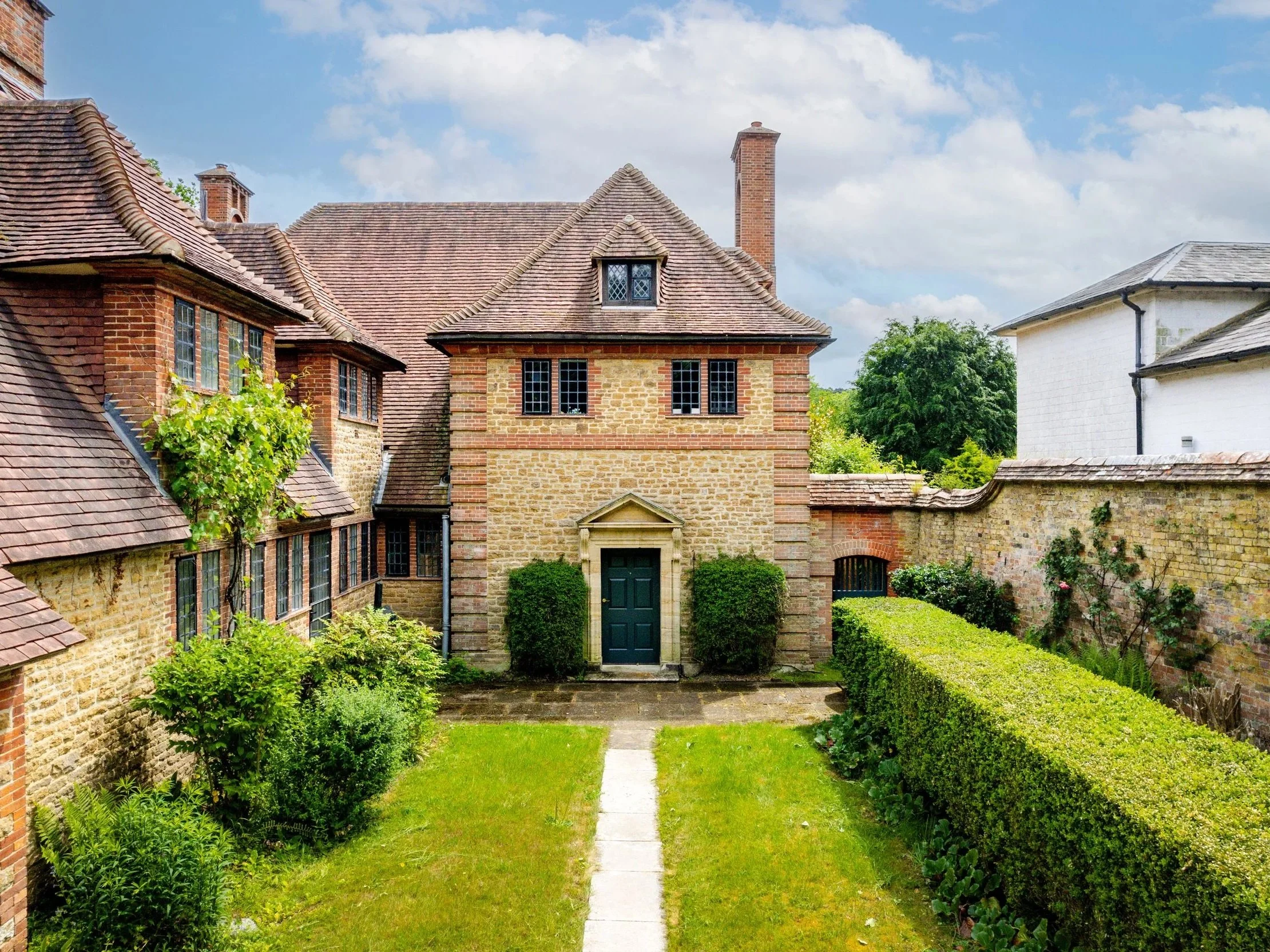 Millmead’s stone-and-brick entrance courtyard in Guildford, with leaded windows, sweeping tiled roofs and a green door.