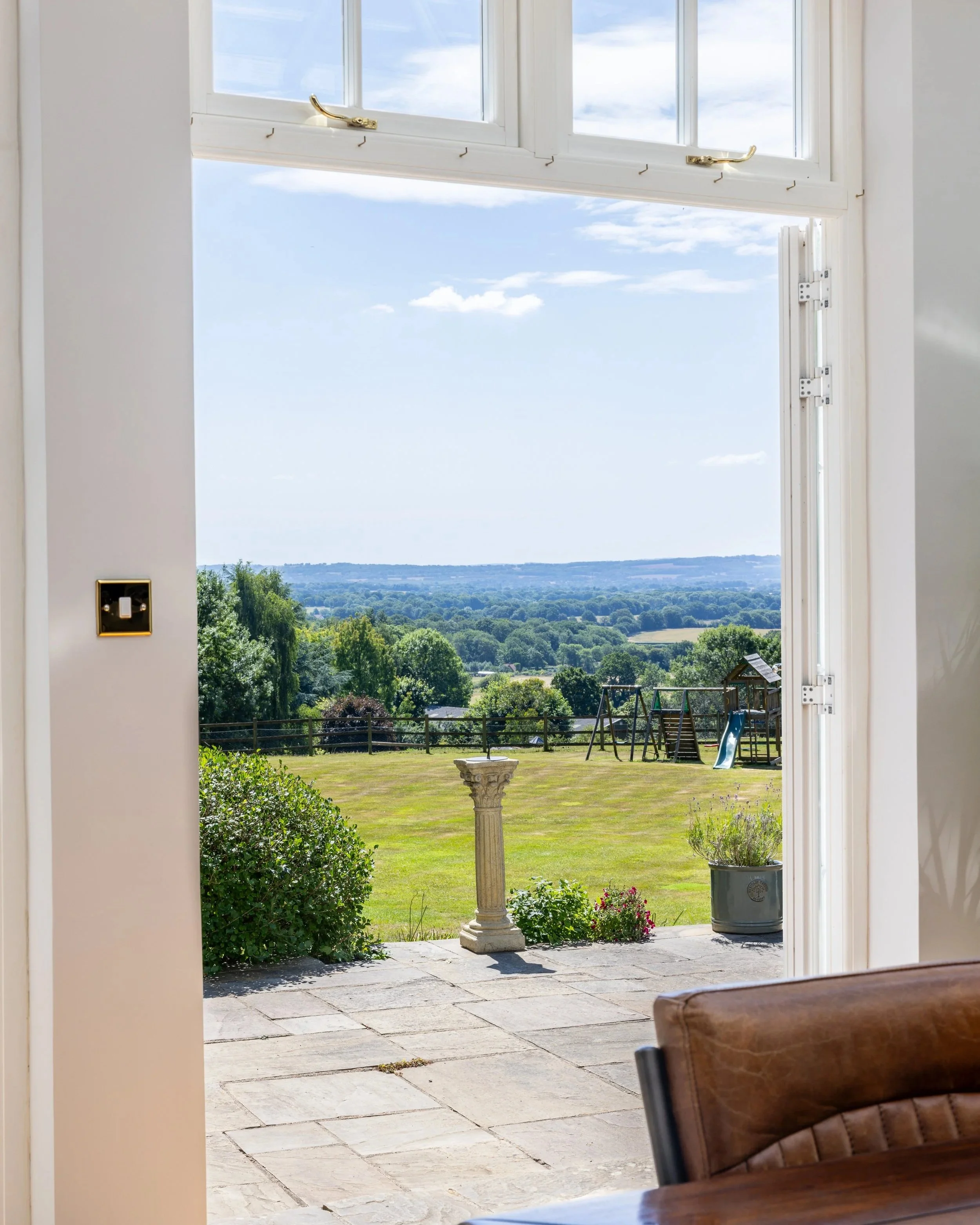 View from the interior of Tandridge Court Lodge through open doors to the garden and countryside.