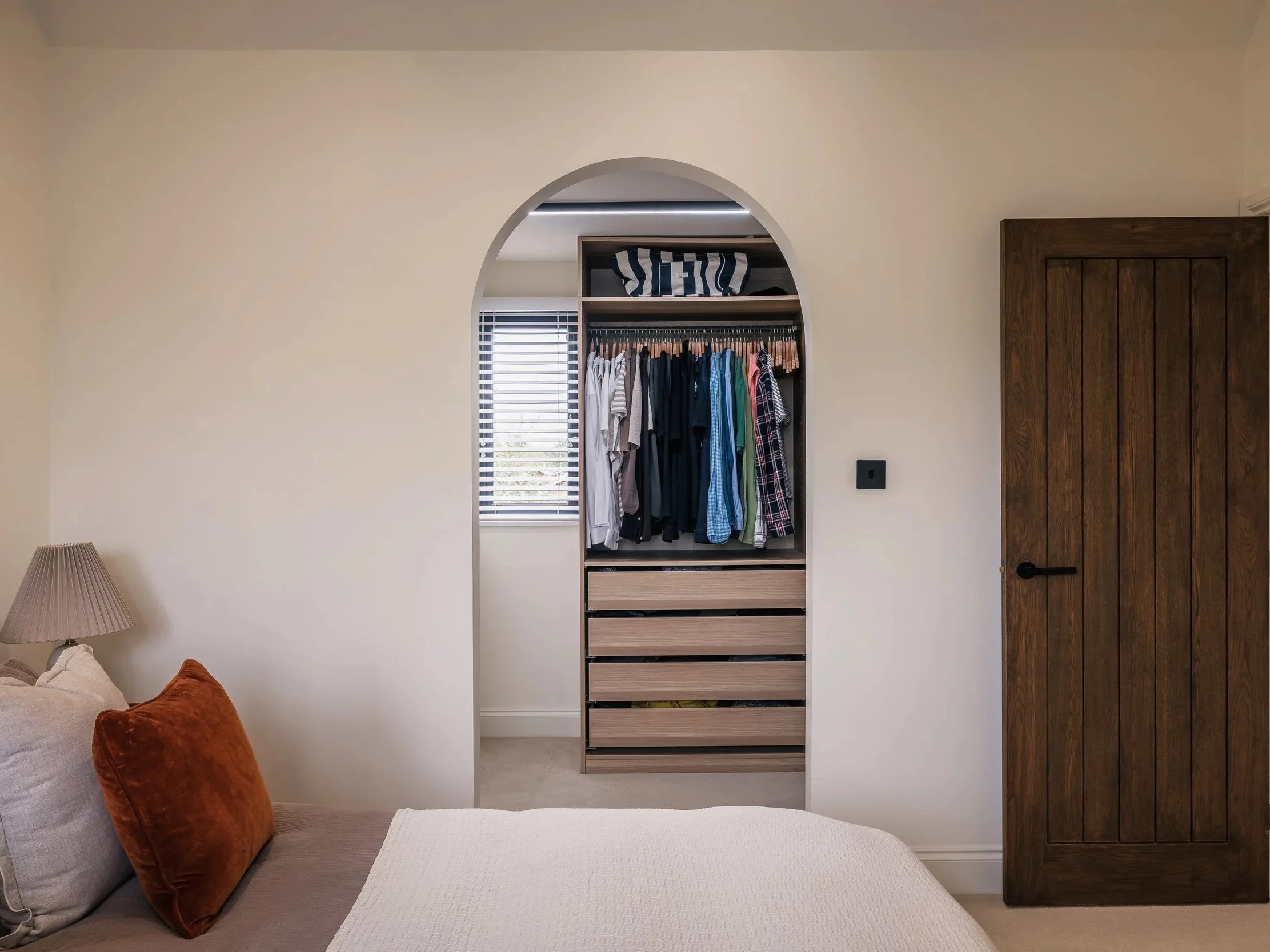 Bedroom at Elwood House with a built-in wardrobe, warm timber door and soft neutral furnishings.