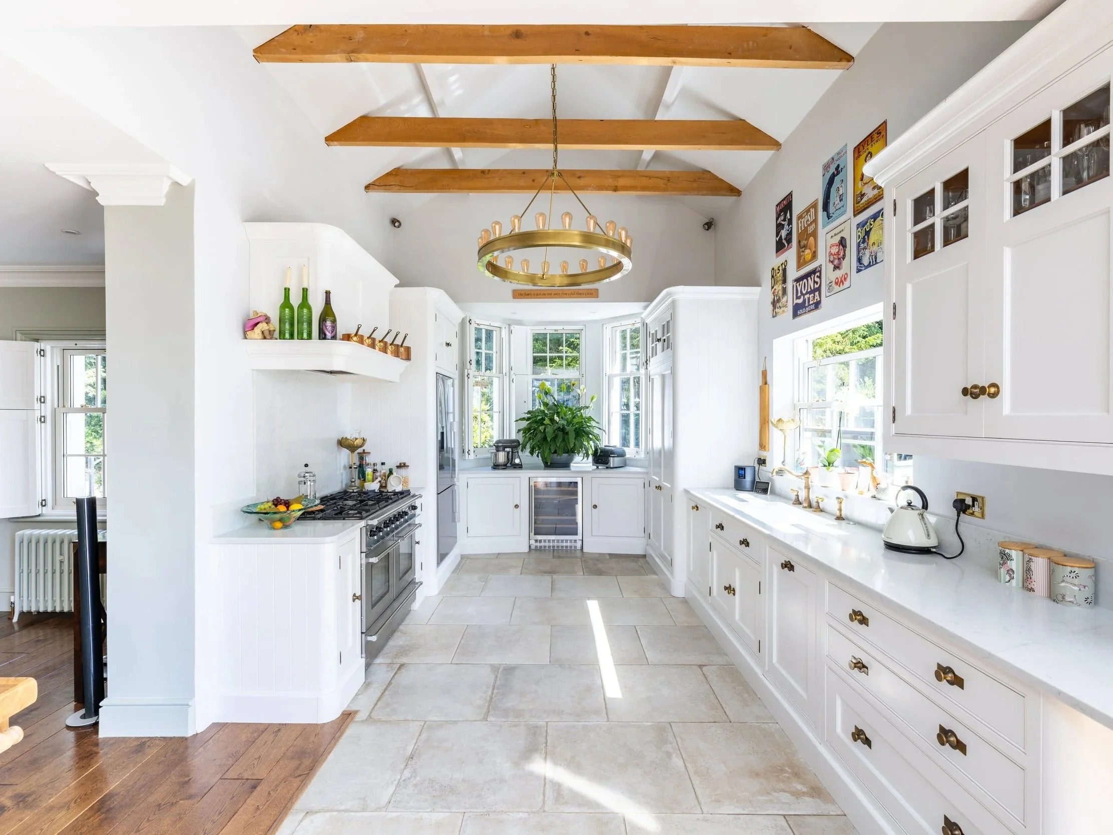 Bright kitchen at Tandridge Court Lodge with white cabinetry, exposed timber beams and a central island.