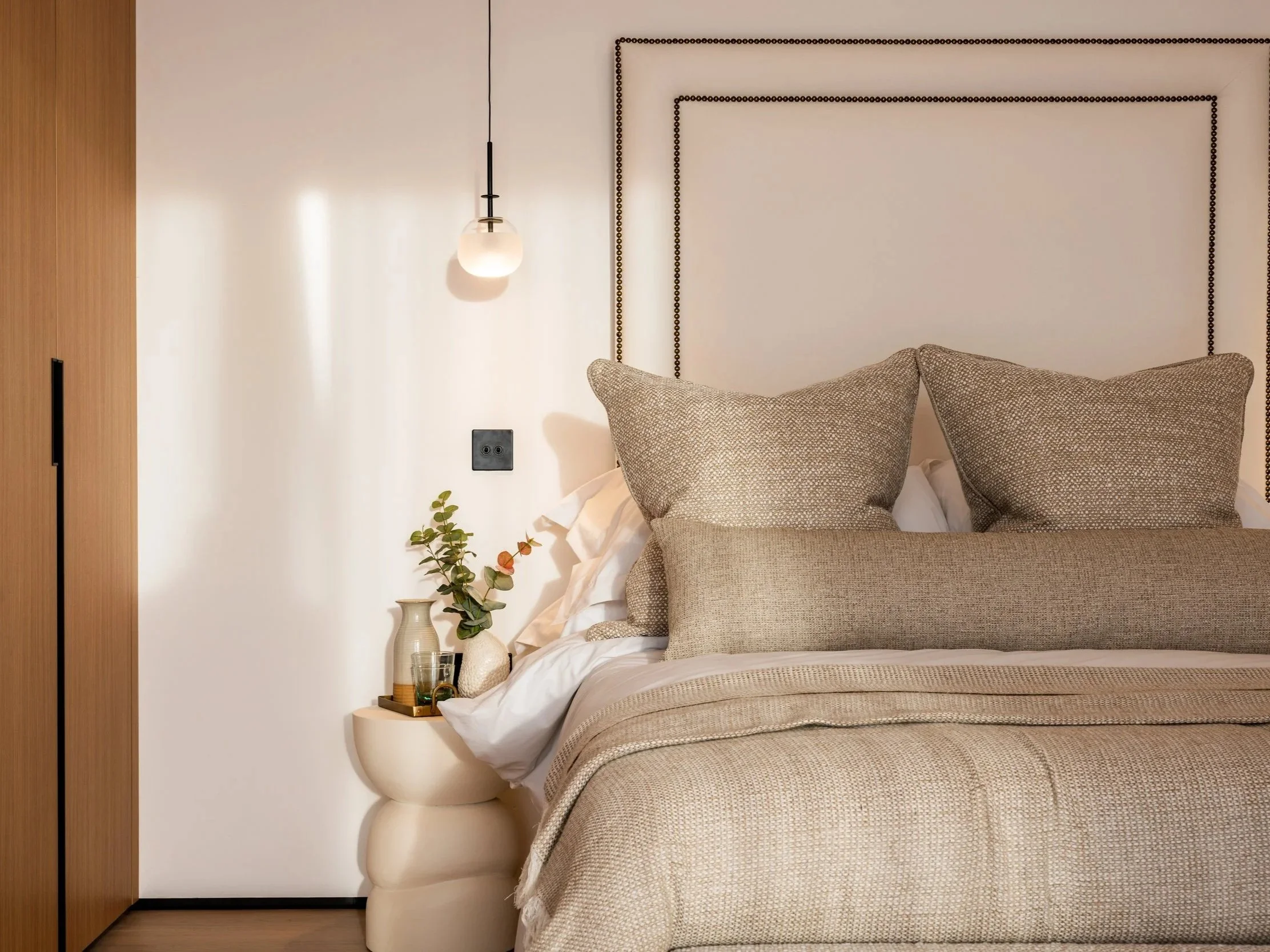Neutral bedroom at Hartdene Barns with an upholstered headboard, timber wardrobe and pendant lighting.