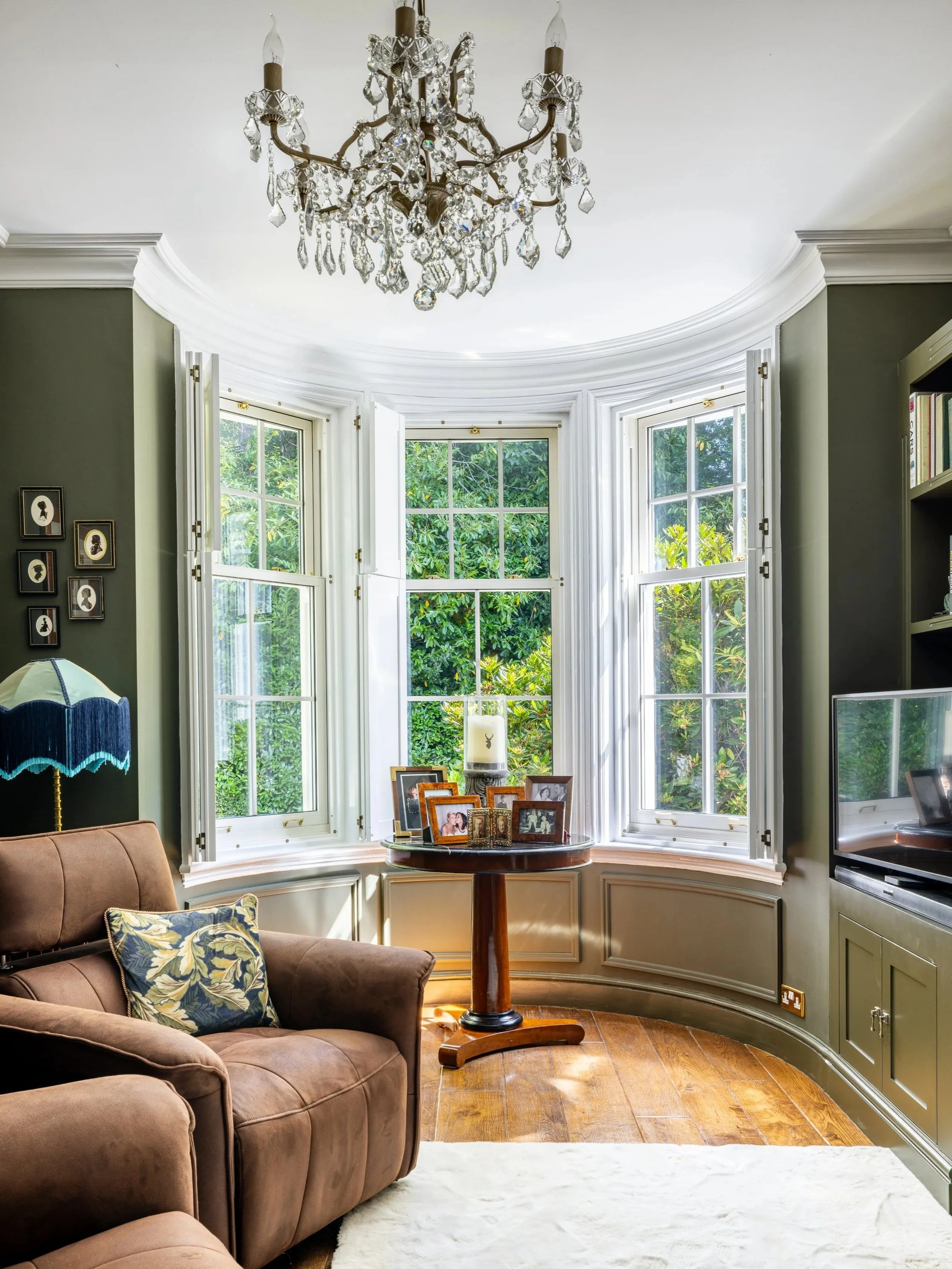 Formal sitting room at Tandridge Court Lodge with an ornate chandelier and tall bay windows.