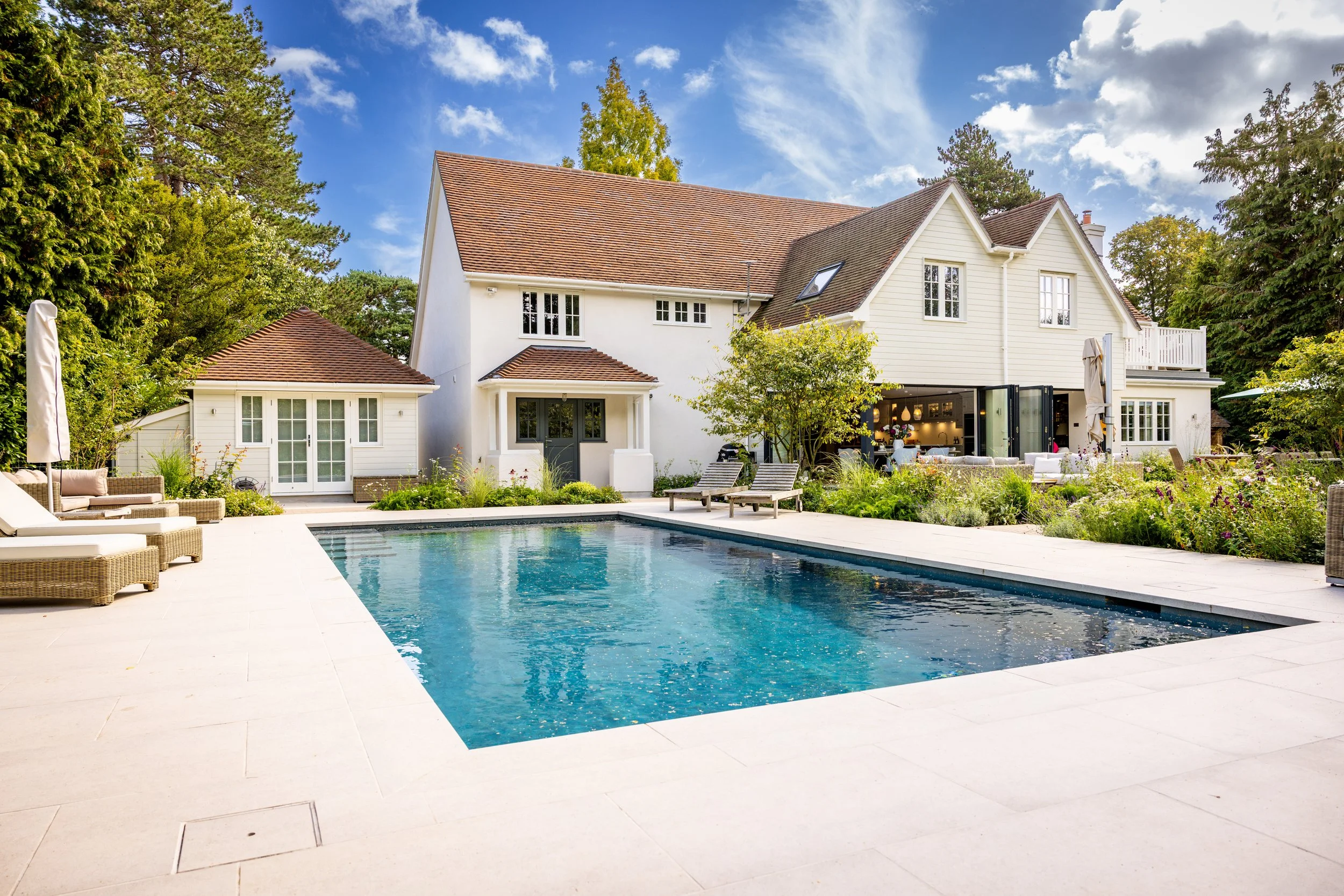 Wide view of the rear house and swimming pool from the garden terrace.