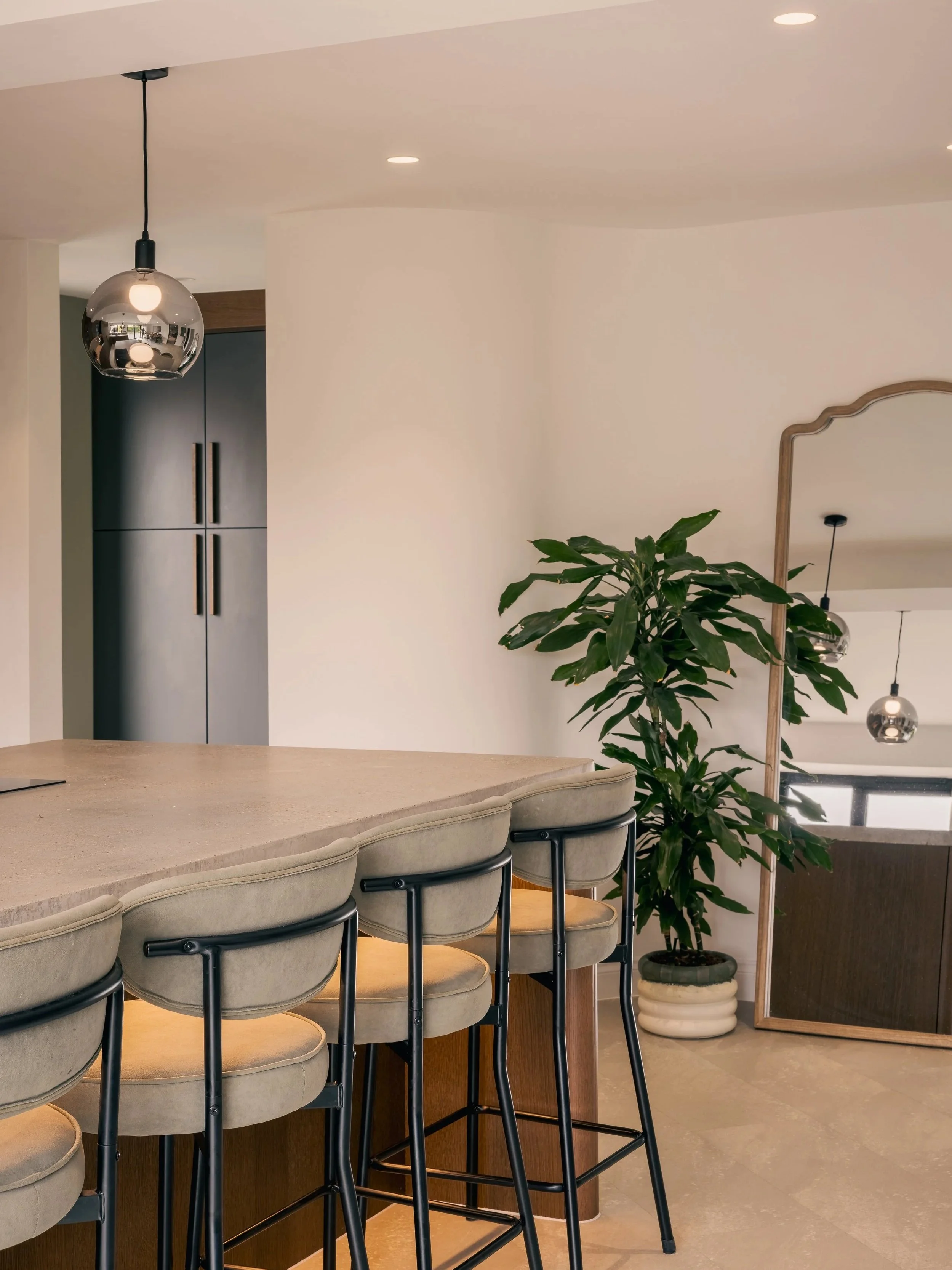 Elwood House kitchen with a large island, dark cabinetry, pendant lighting and bar stools.