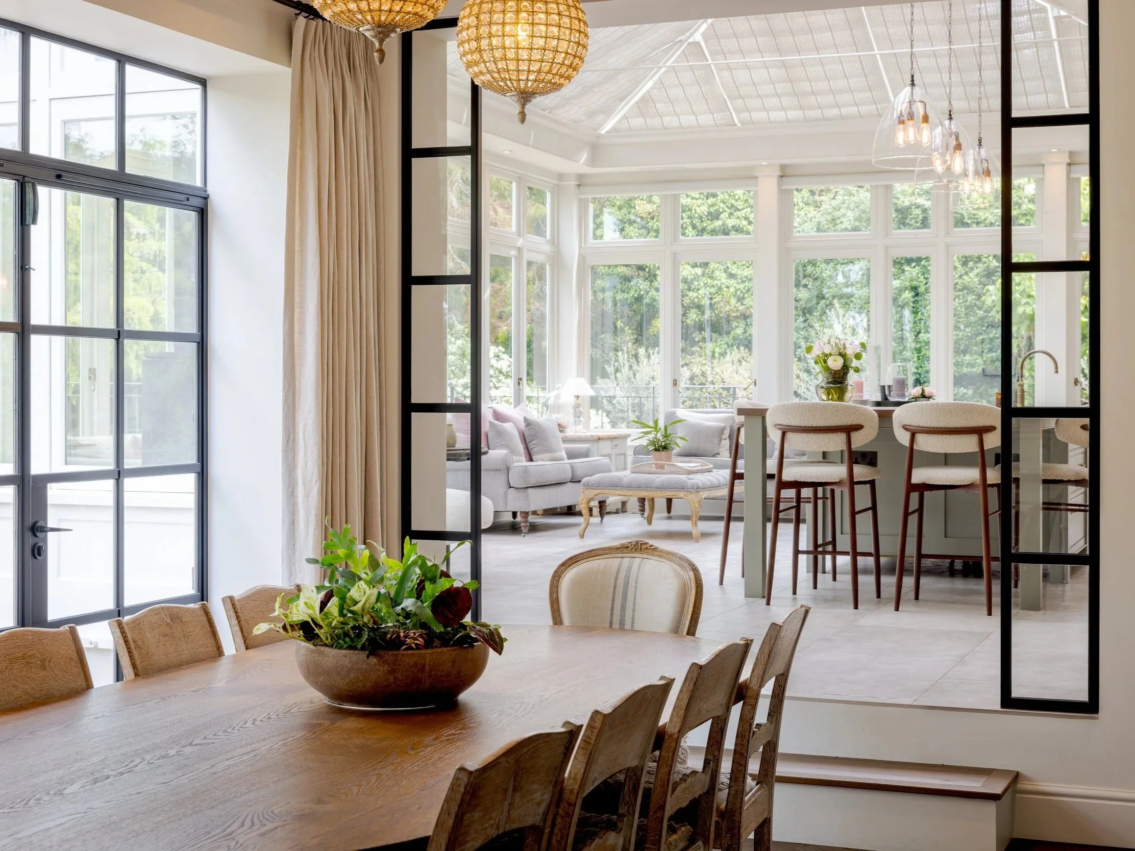 Dining room looking through black-framed doors towards the kitchen and garden room at Albury Road.