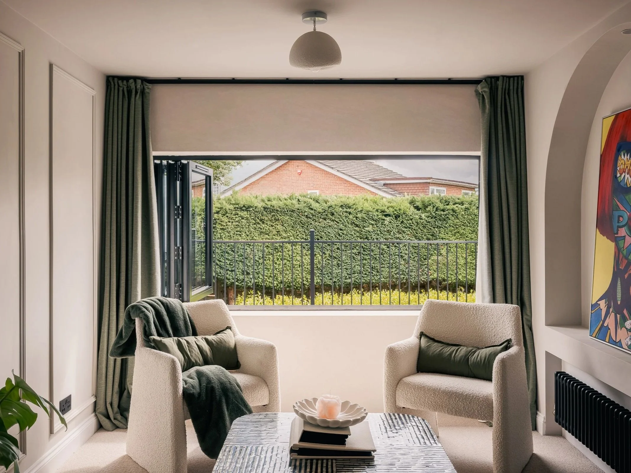 Two upholstered chairs and a coffee table beside open garden-facing doors.