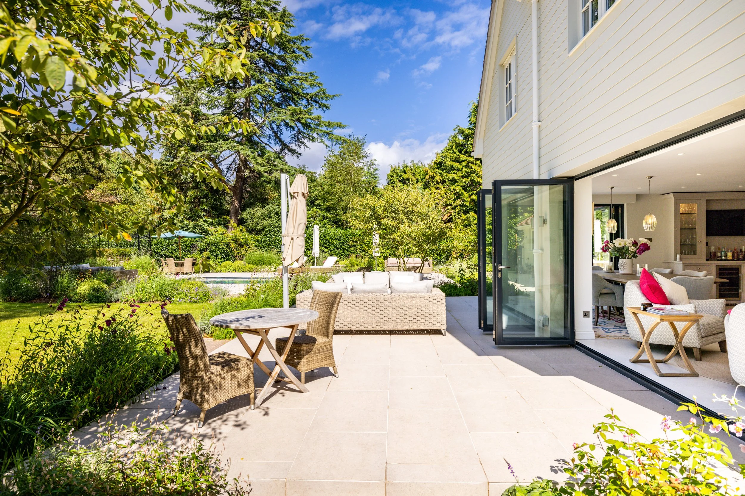 Rear patio seating beside open folding doors and the garden.