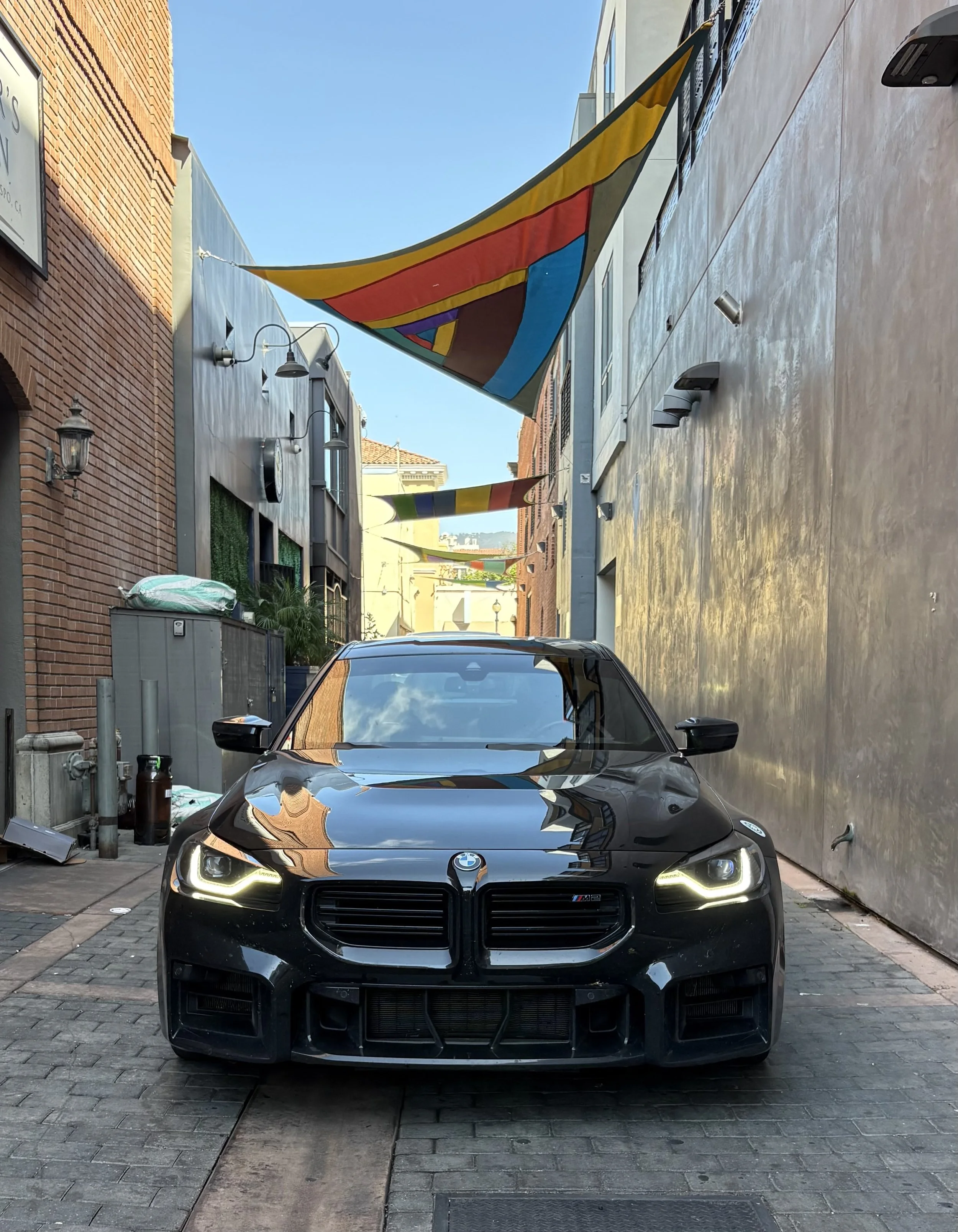 black-bmw-m5-sedan-parked-in-narrow-alley-with-colorful-flags--962fae95.jpeg