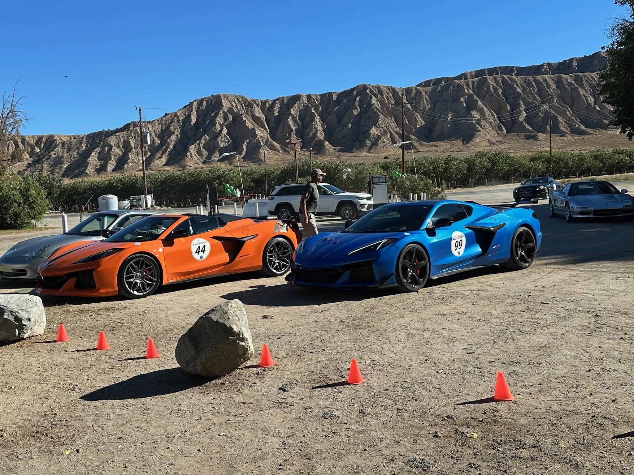 orange-blue-rally-cars-parked-on-dirt-near-mountains--7178b85c.jpeg