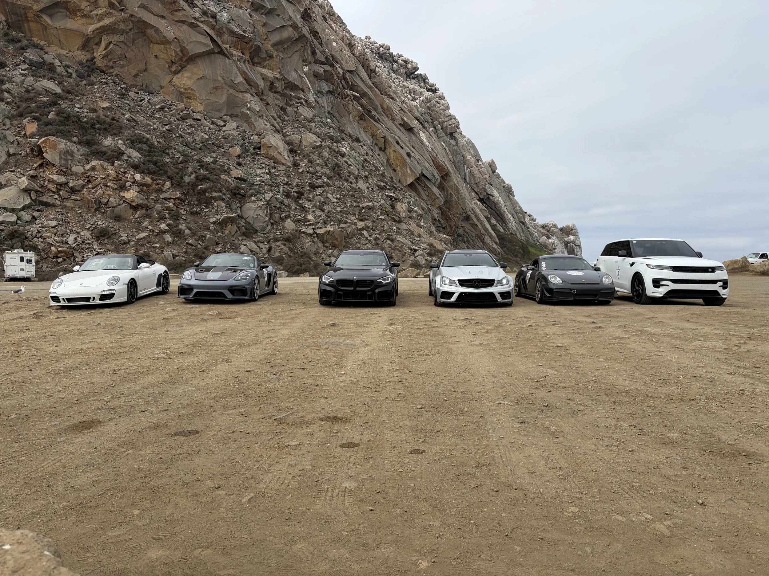 six-rally-cars-parked-beneath-a-towering-rocky-outcrop--b003bb0e.jpeg
