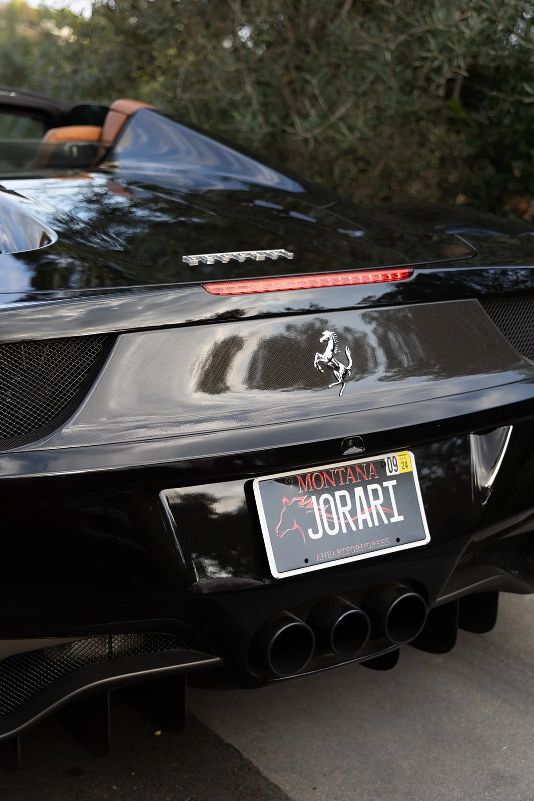 Black Ferrari with Montana license plate reading 'JORARI' and a prancing horse emblem on the back.