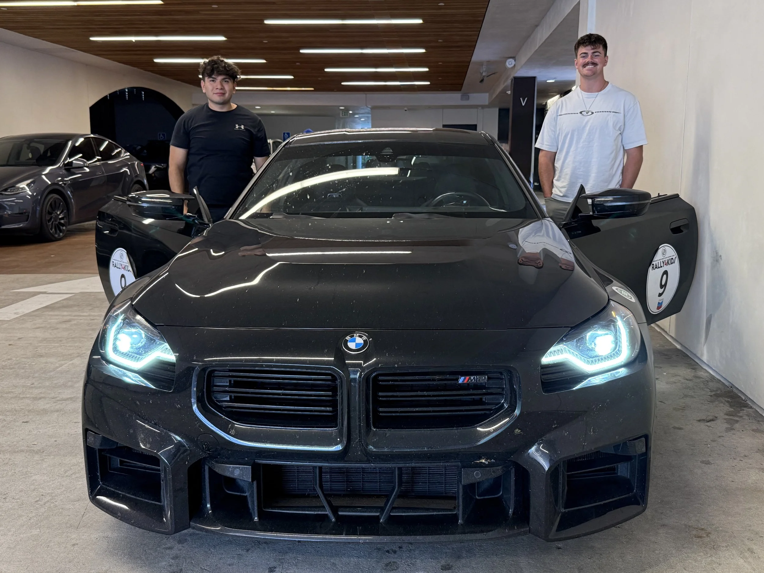 black-bmw-m2-with-open-doors-and-two-men-standing-beside-it--3a5c7967.jpeg