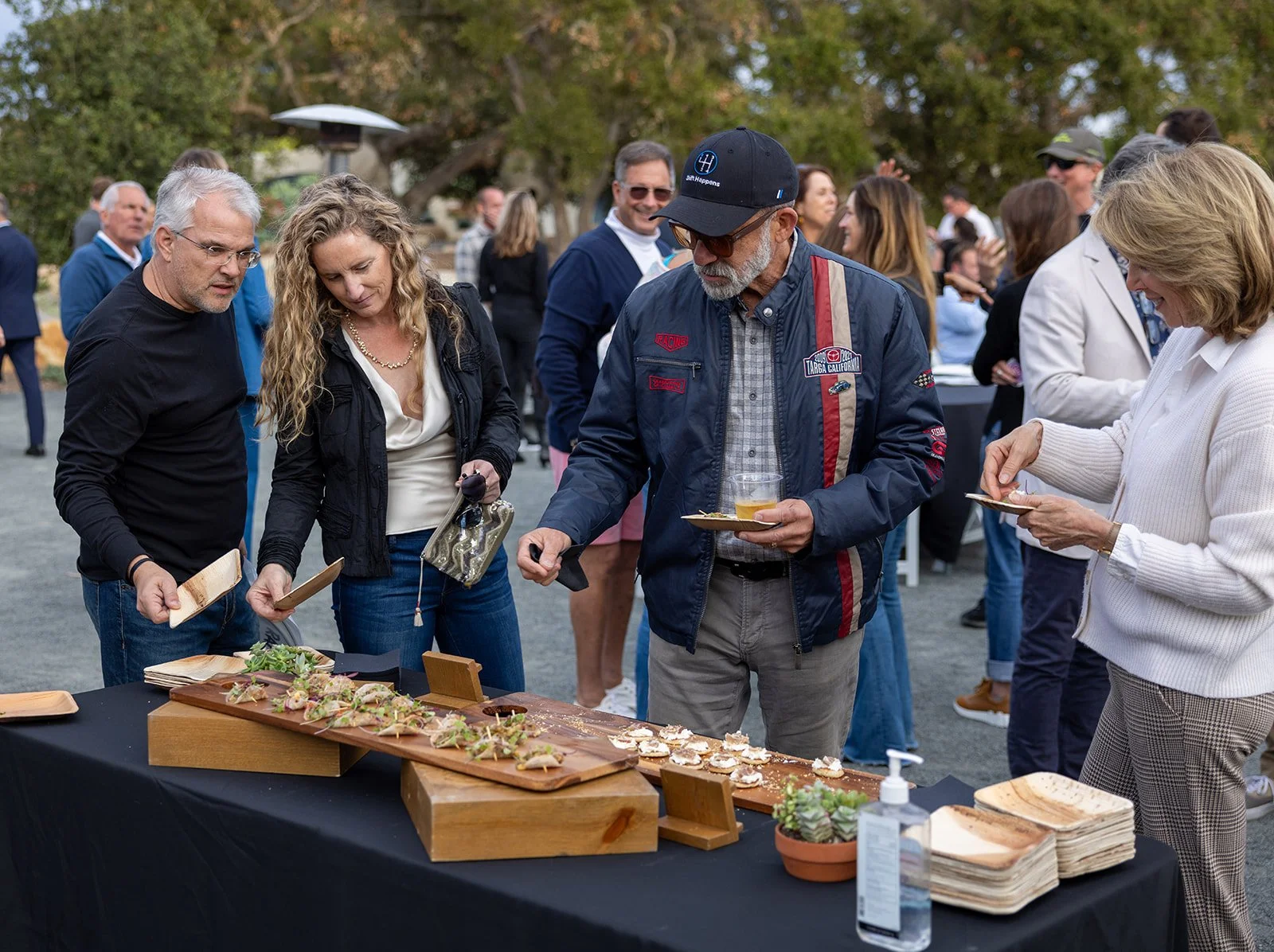 People gathered around a table enjoying appetizers at an outdoor event.