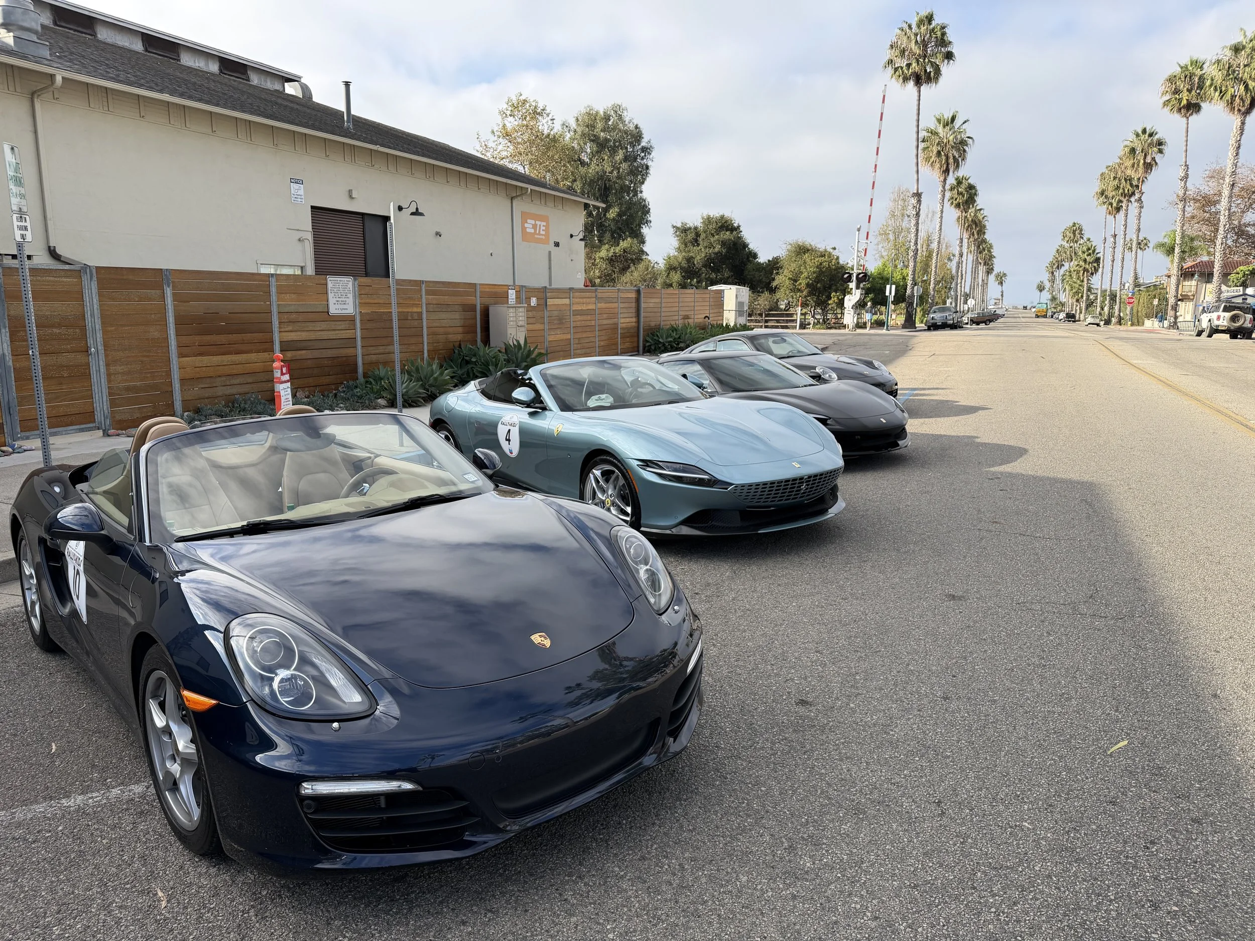 black-porsche-convertible-leading-a-palm-lined-car-lineup--90efc24c.jpeg