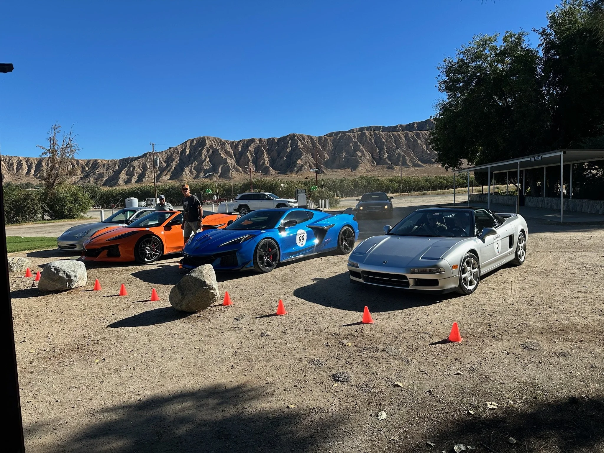 blue-orange-and-silver-sports-cars-parked-on-dirt-with-cones--55c8dbbb.jpeg