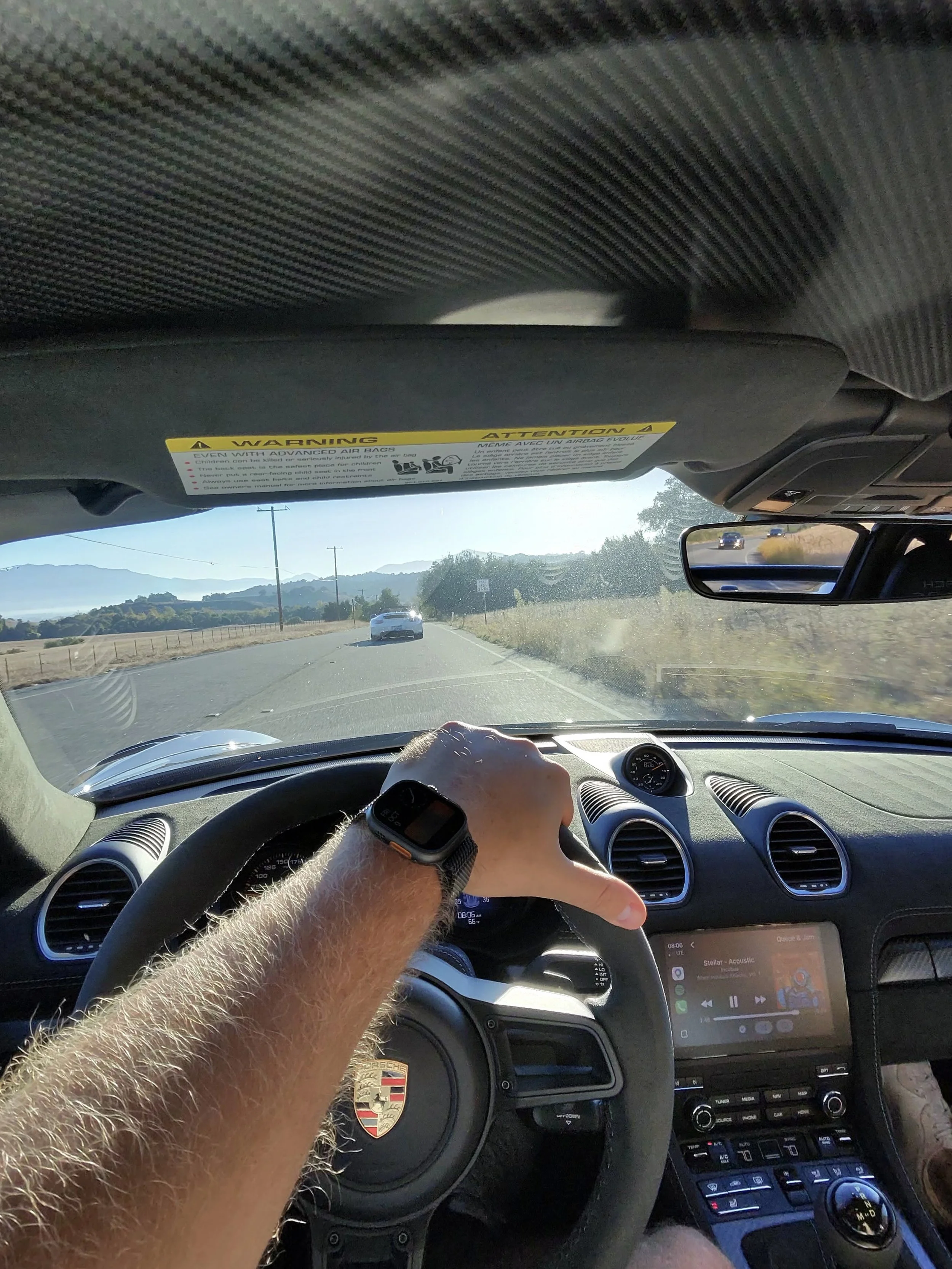 drivers-hand-on-porsche-steering-wheel-along-open-highway--85d2427e.jpeg