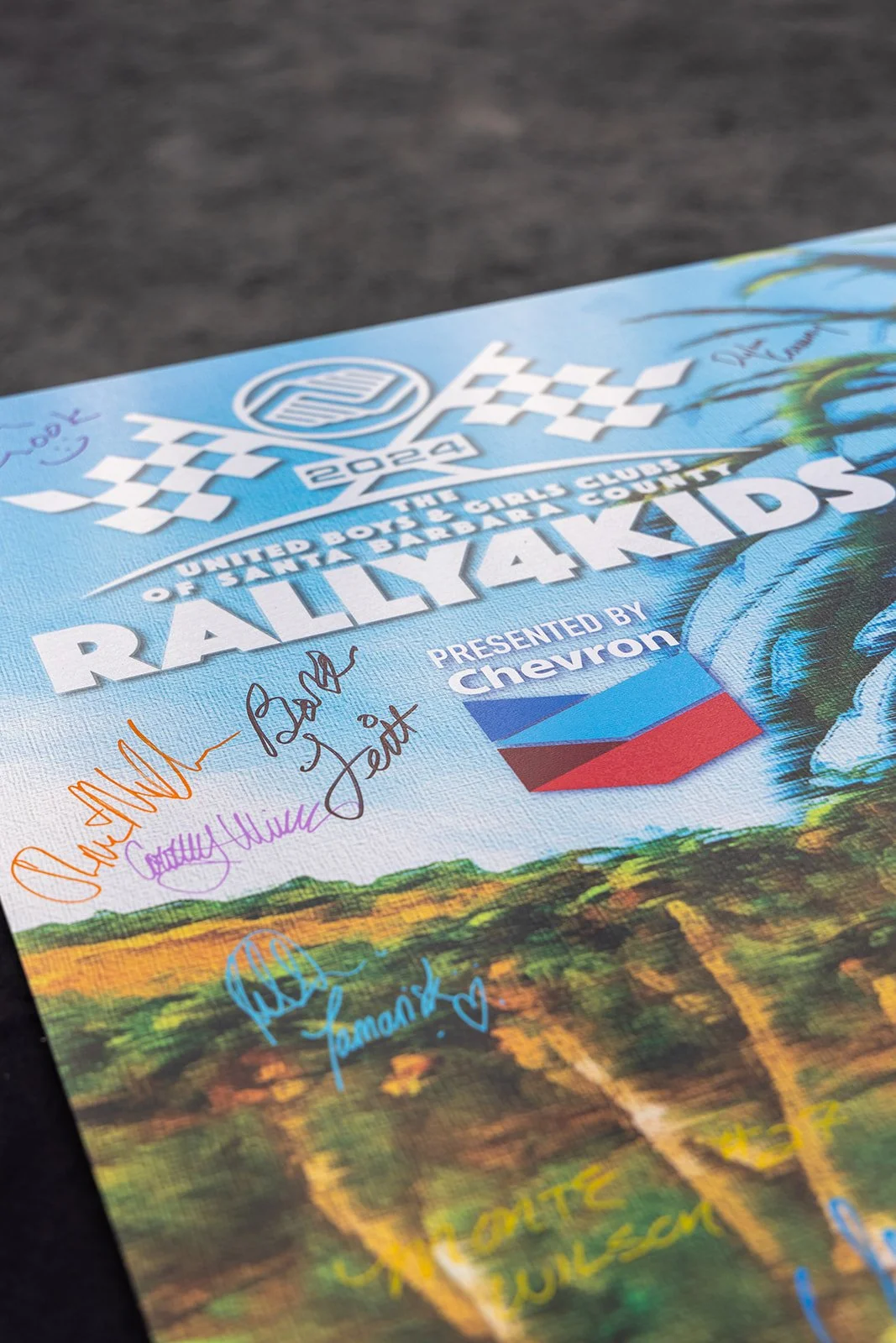 2022 Rally4Kids poster from the United Boys & Girls Club of Salt Lake County with signatures and a Chevrolet logo, featuring a scenic background of a vineyard or farm landscape.