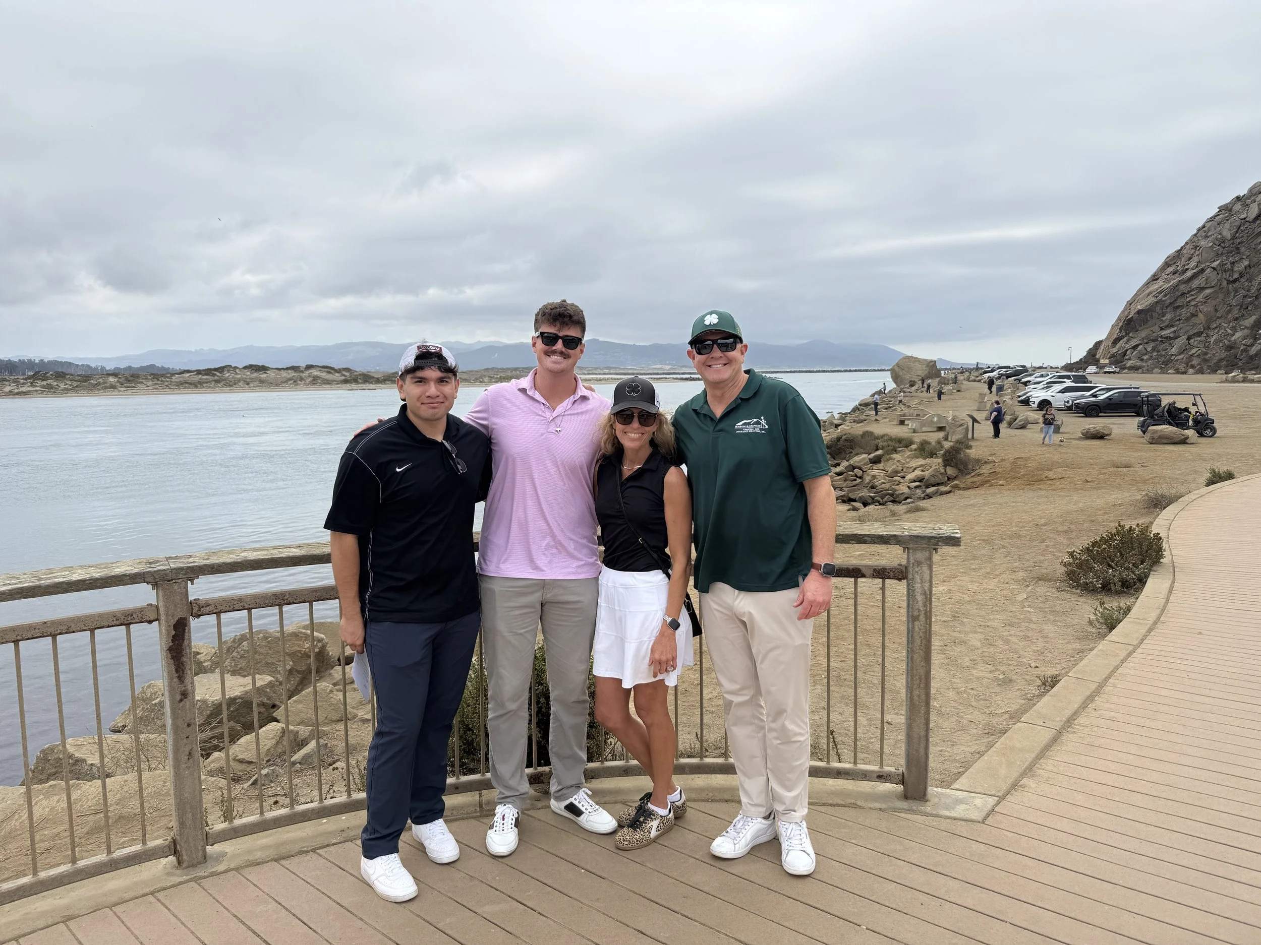 four-people-standing-on-a-wooden-deck-by-the-water--1cf8017b.jpeg