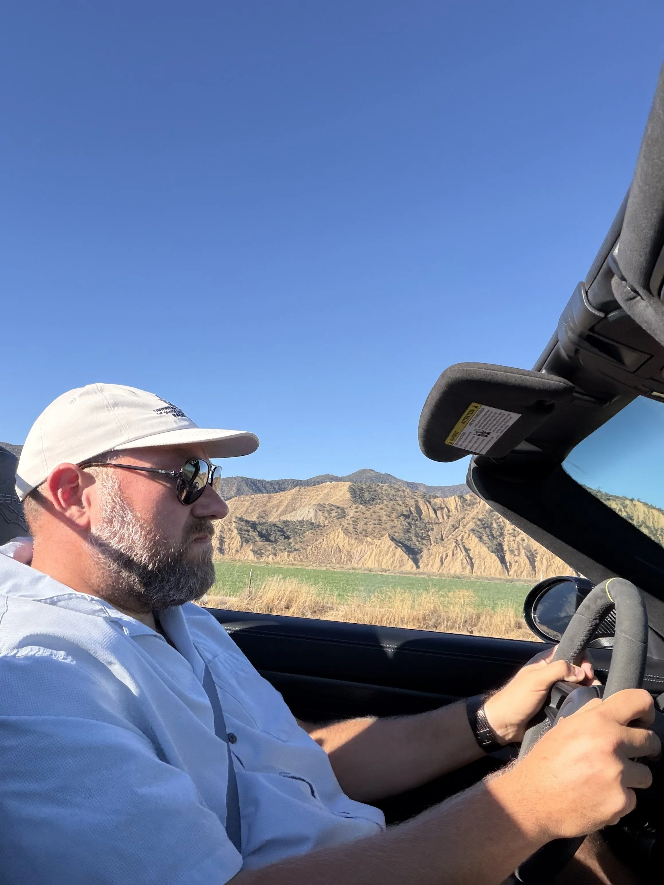bearded-driver-in-white-cap-behind-convertible-wheel--bbdf88cc.jpeg