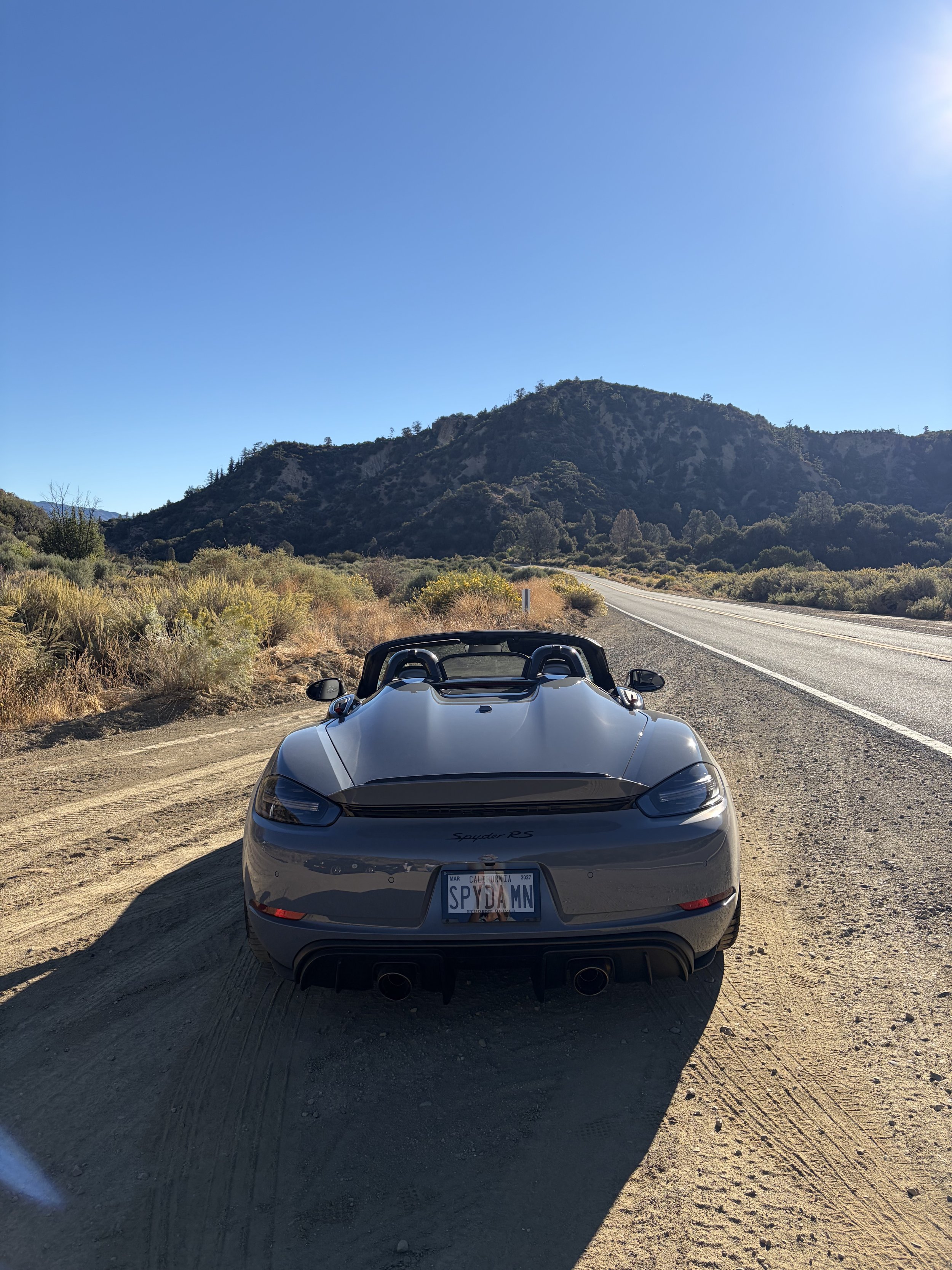 gray-convertible-parked-on-dirt-shoulder-below-rocky-hills--b90b0d98.jpeg