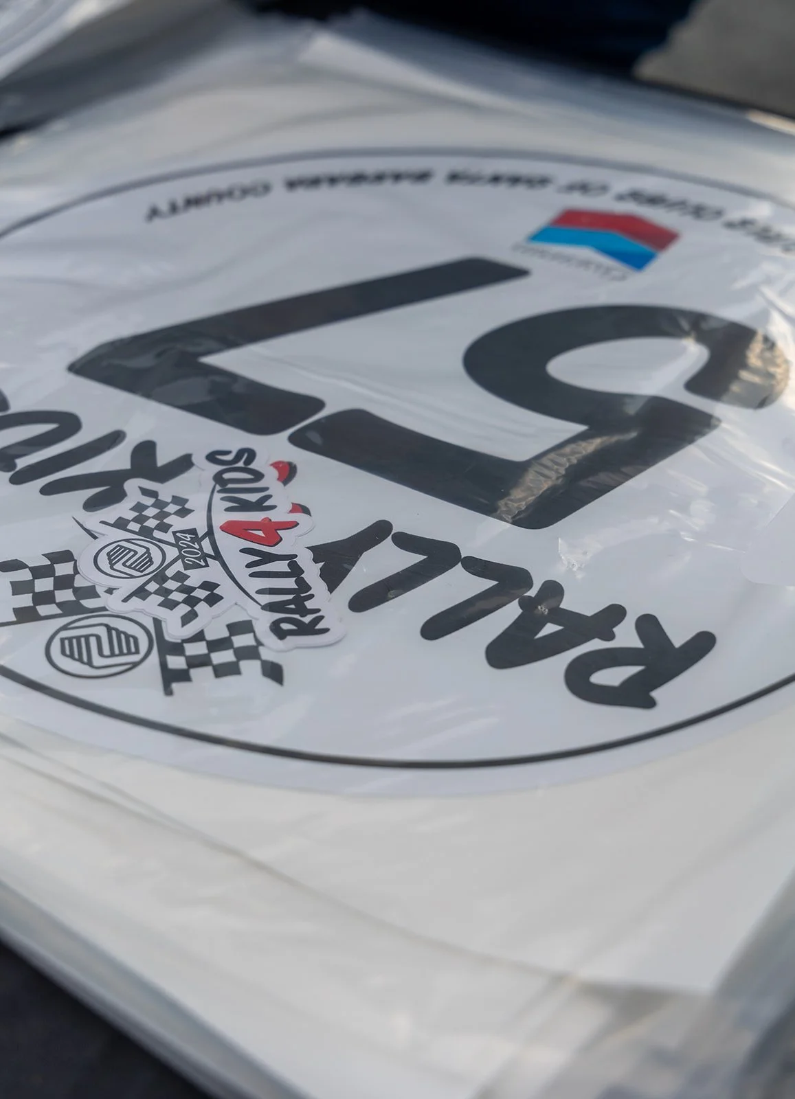 Close-up of a racing sticker with the number 77, checkered flags, and the words 'RALLY RACING 44.'