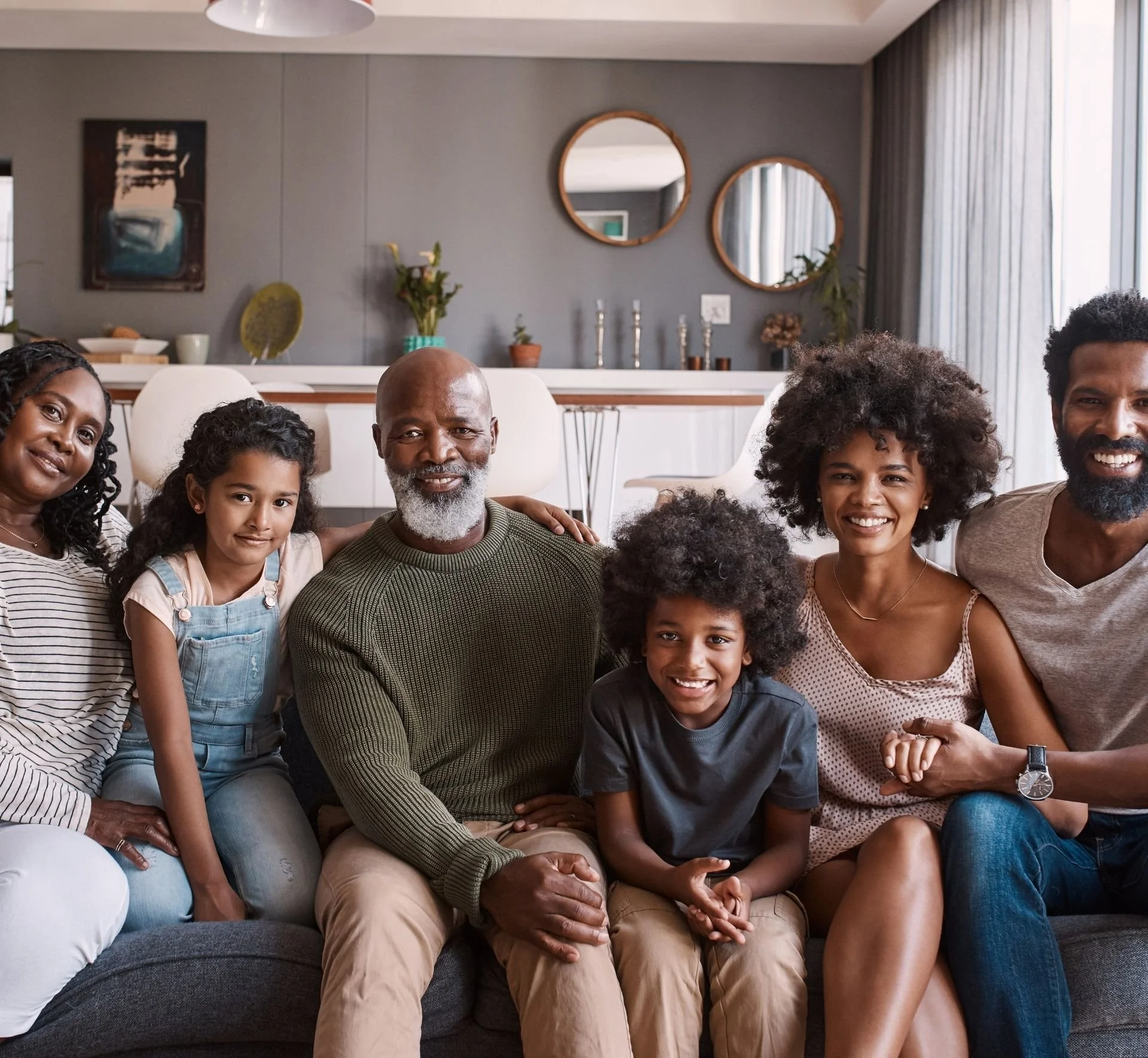 Family sitting on a sofa in a modern living room, smiling at the camera.