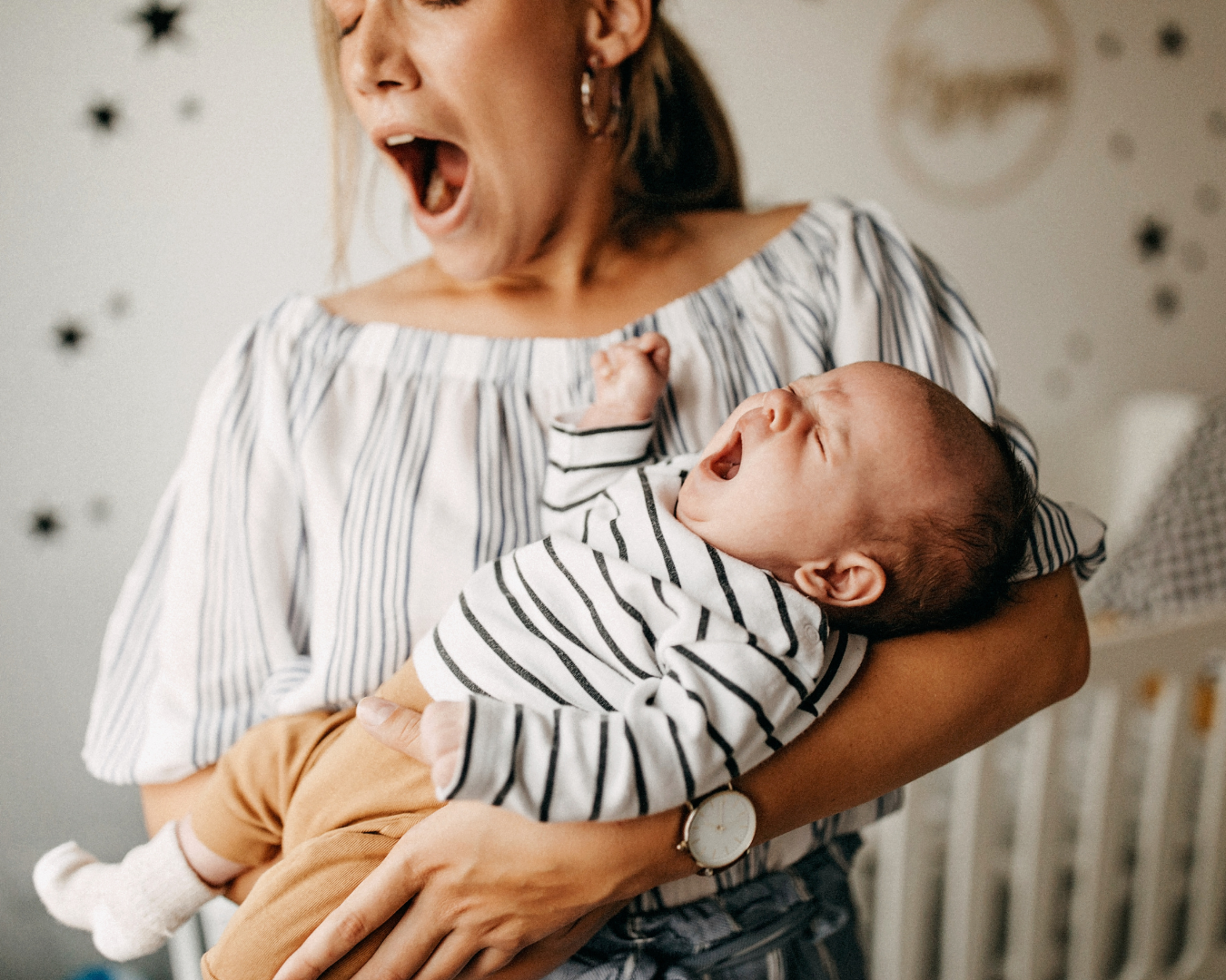 Sleep-deprived mother holding her newborn baby, illustrating postpartum exhaustion, newborn sleep challenges, and parental mental health.