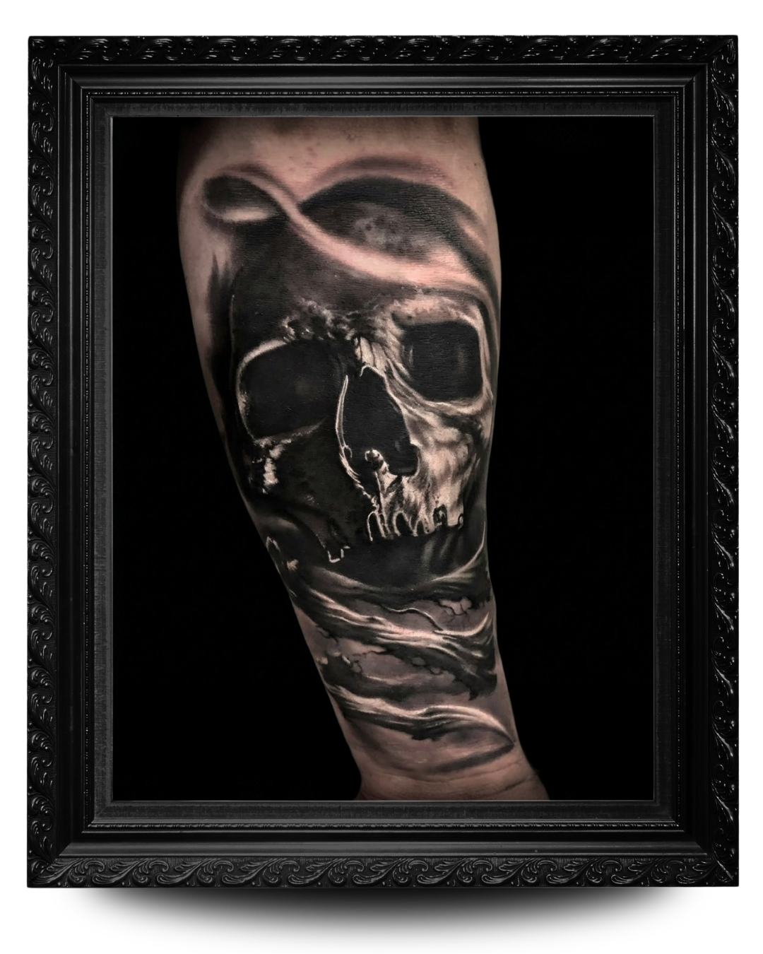 Black and gray tattoo of a skull with a landscape scene, including waves and clouds, on a person's arm.