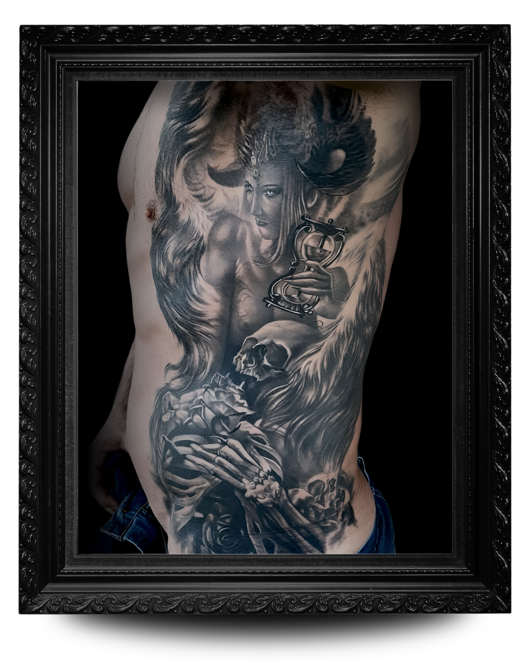 Black and gray tattoo on a person's torso featuring a woman with long hair holding an hourglass, surrounded by a wolf, a skull, and skeletal hands, framed in a decorative black frame.
