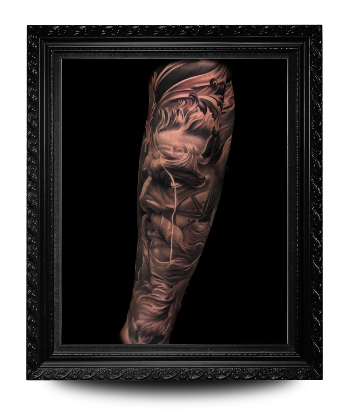 Close-up of a detailed black and gray tattoo sleeve on a person's arm, featuring a woman's face, abstract smoke, and geometric elements, framed in a decorative black picture frame.