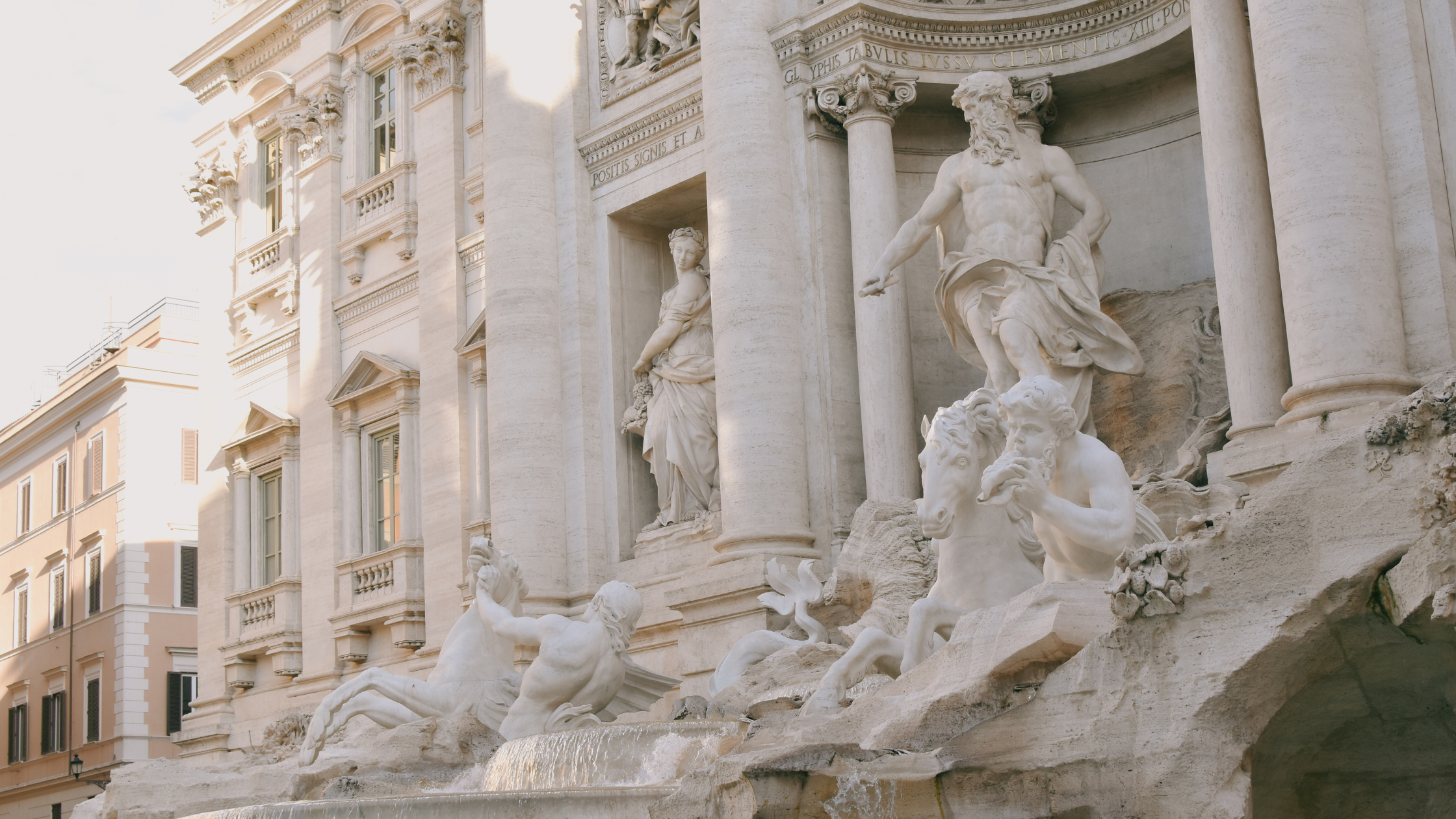 Close-up view of the Fontana dei Quattro Fiumi (Fountain of the Four Rivers) in Rome, Italy, with intricate marble statues of mythological figures, including a river god and a woman, set against a backdrop of classical buildings.