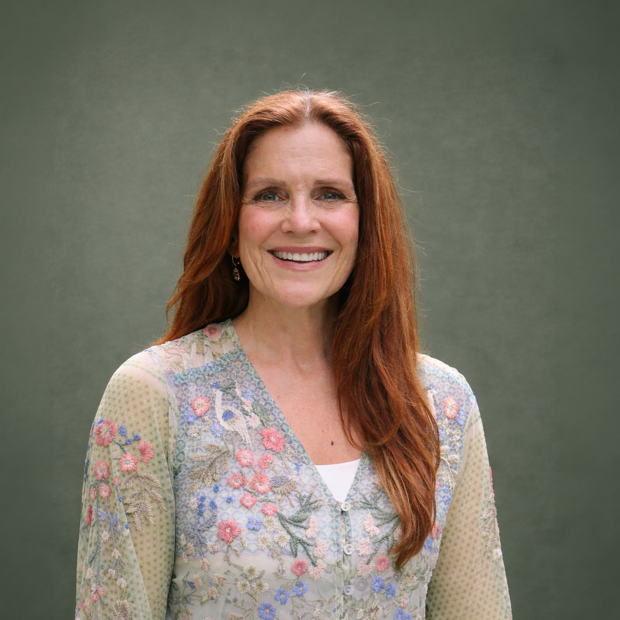 Headshot of smiling female with long red hair hair wearing a lanyard.