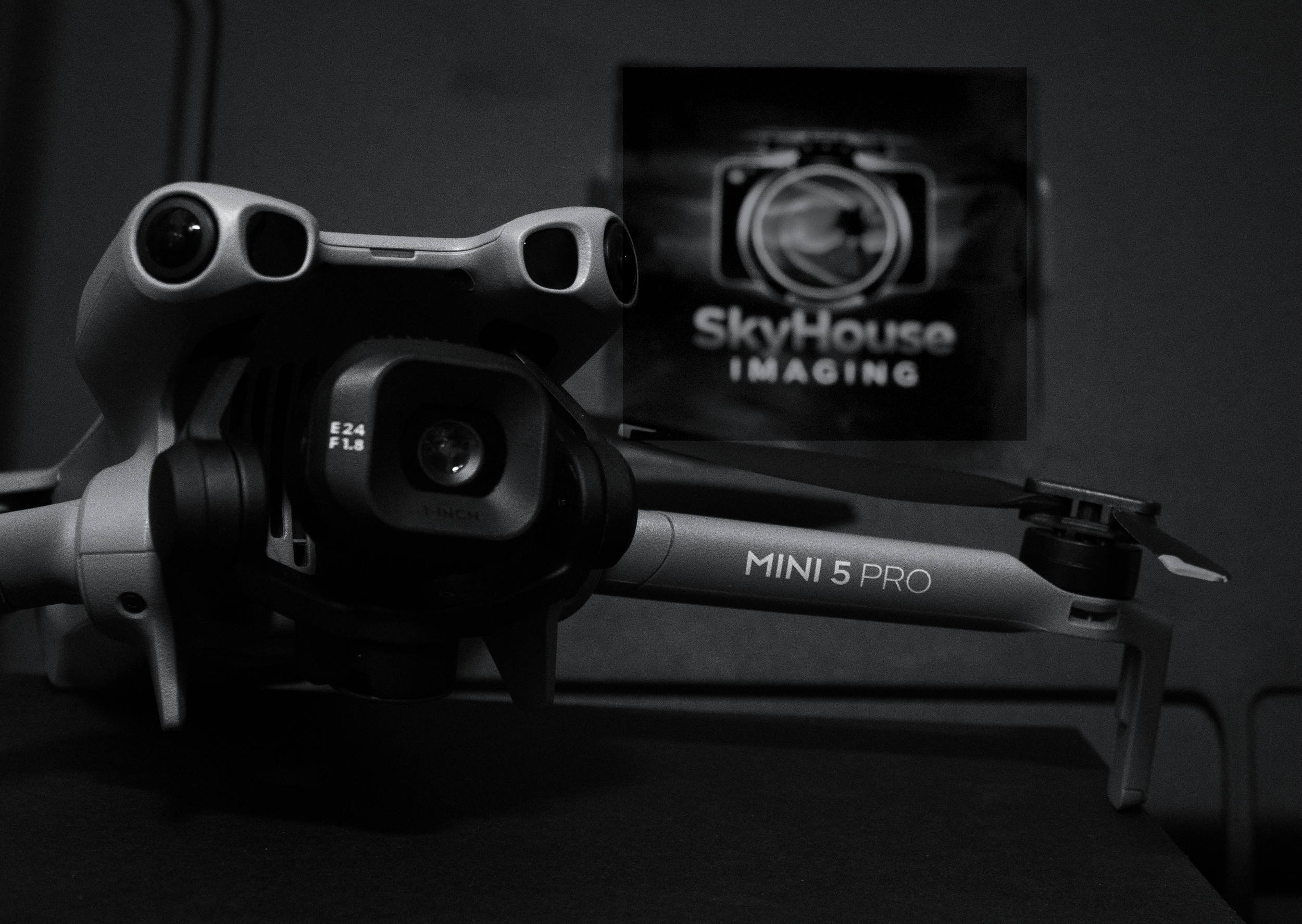 A drone with a camera mounted on it, placed in front of a box labeled SkyHouse Imaging.
