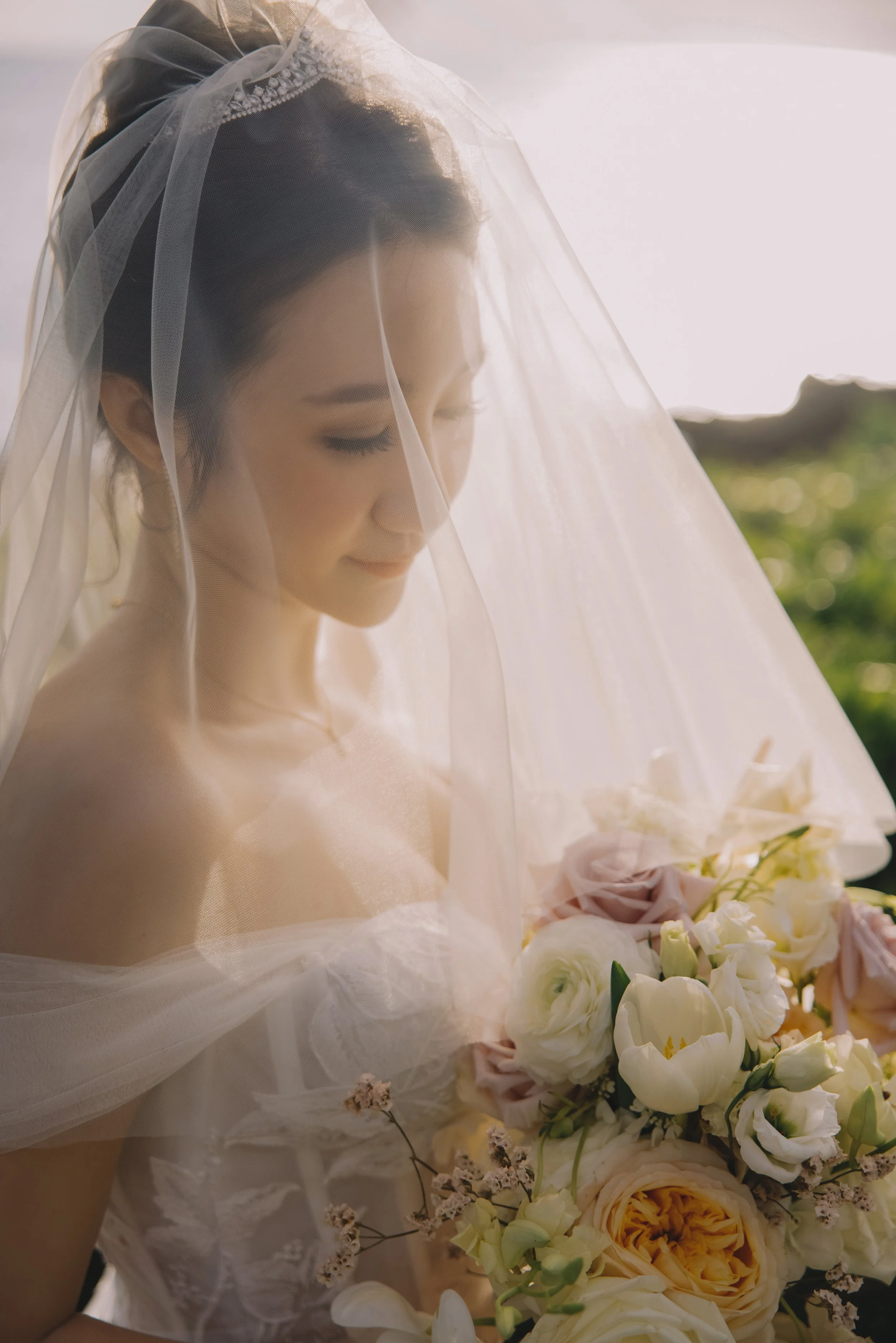 Bride with a veil holding a bouquet of white and blush flowers