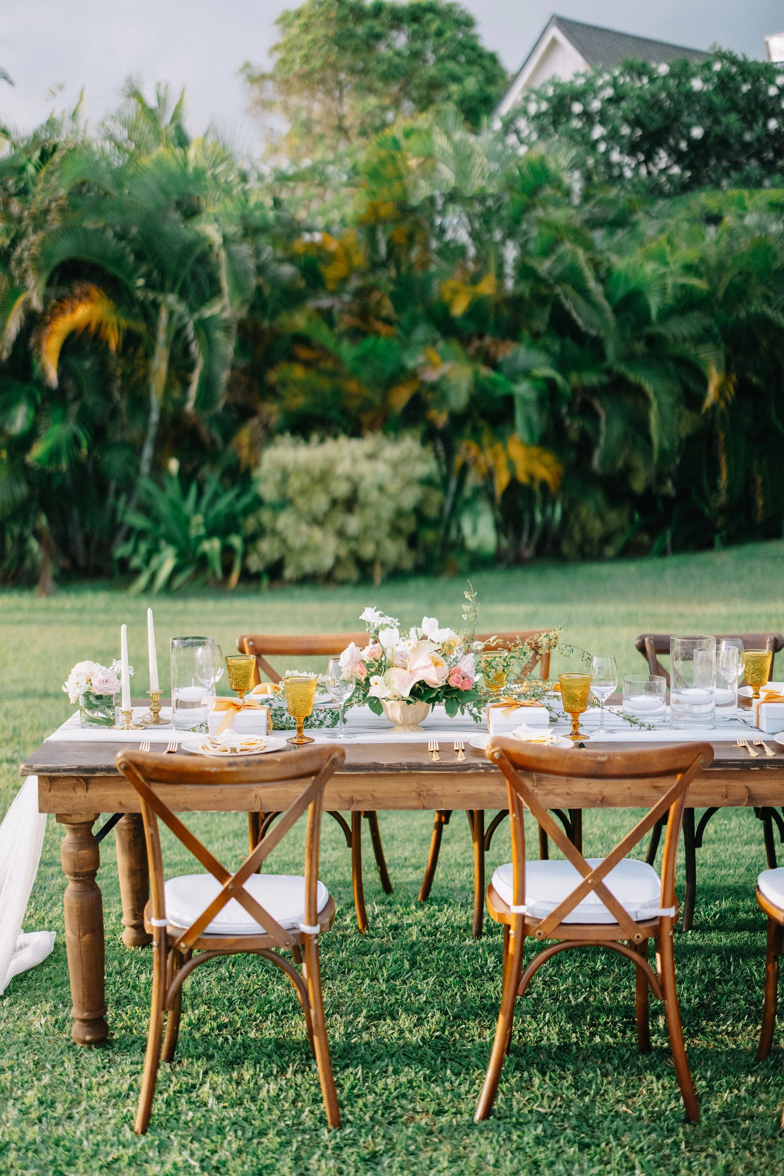 Outdoor dining table decorated with flowers, candles, and glassware.
